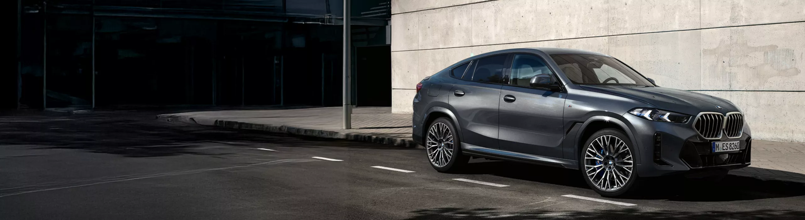 BMW X6停在陽光下在磚建築前