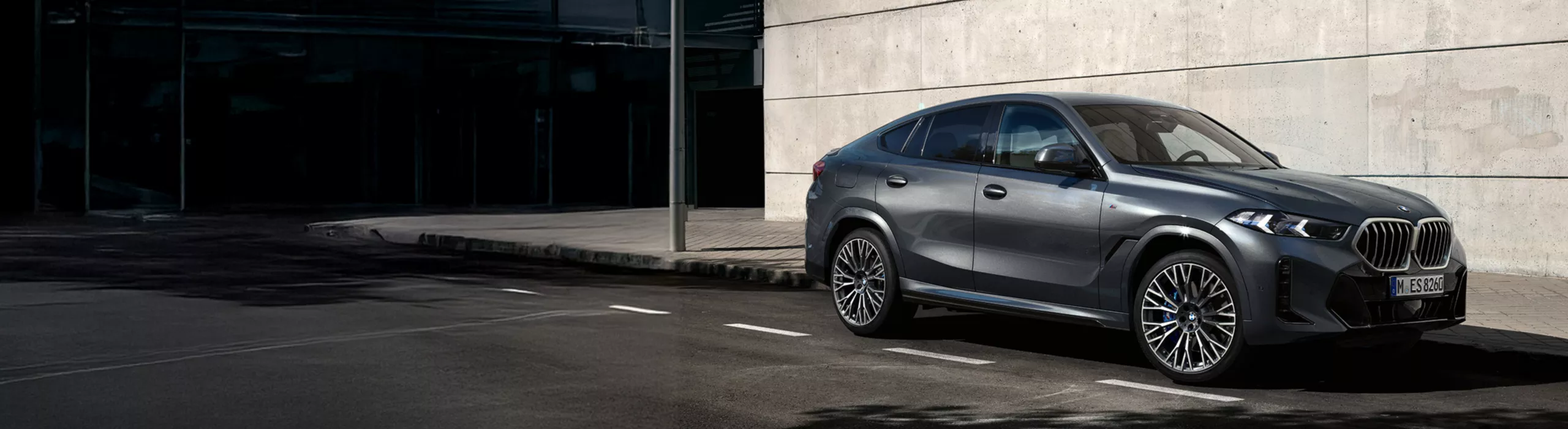 BMW X6停在陽光下在磚建築前