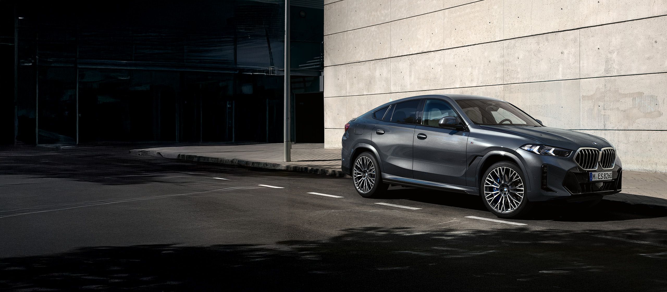 BMW X6停在陽光下在磚建築前