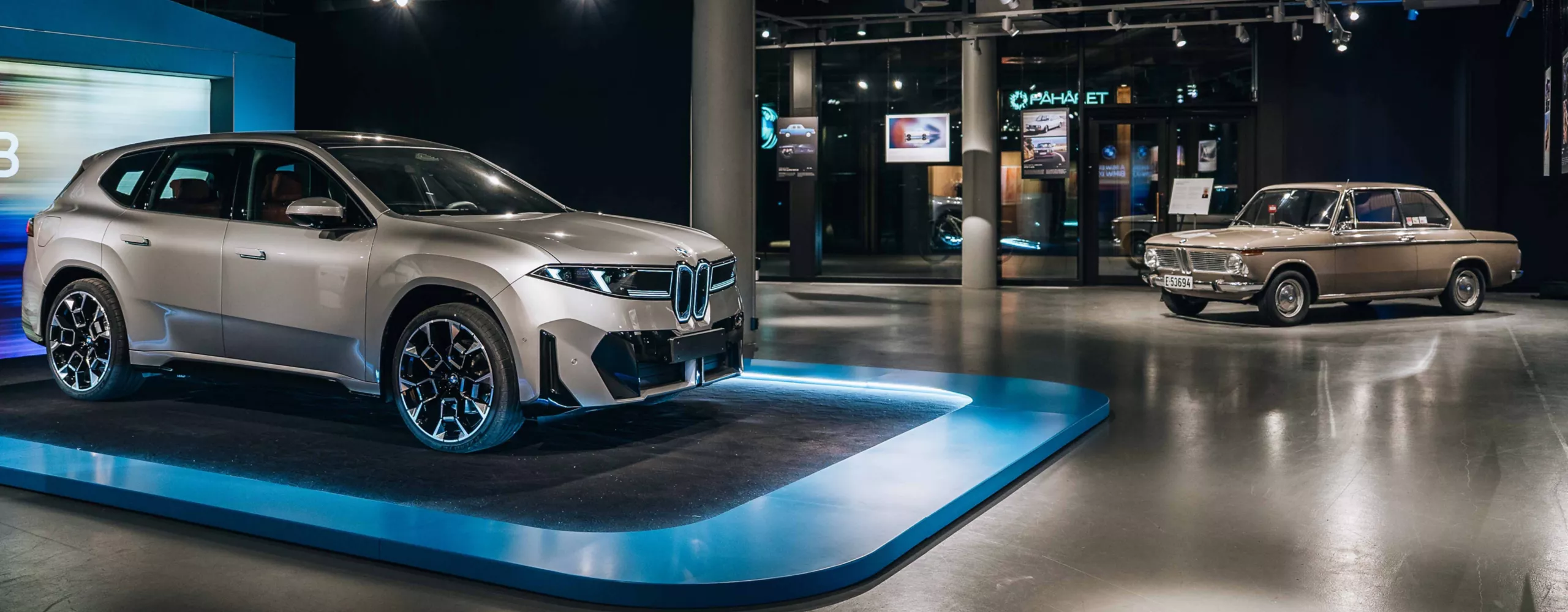 En grå BMW iX3 sedd från sidan, och en beige BMW 1600-2