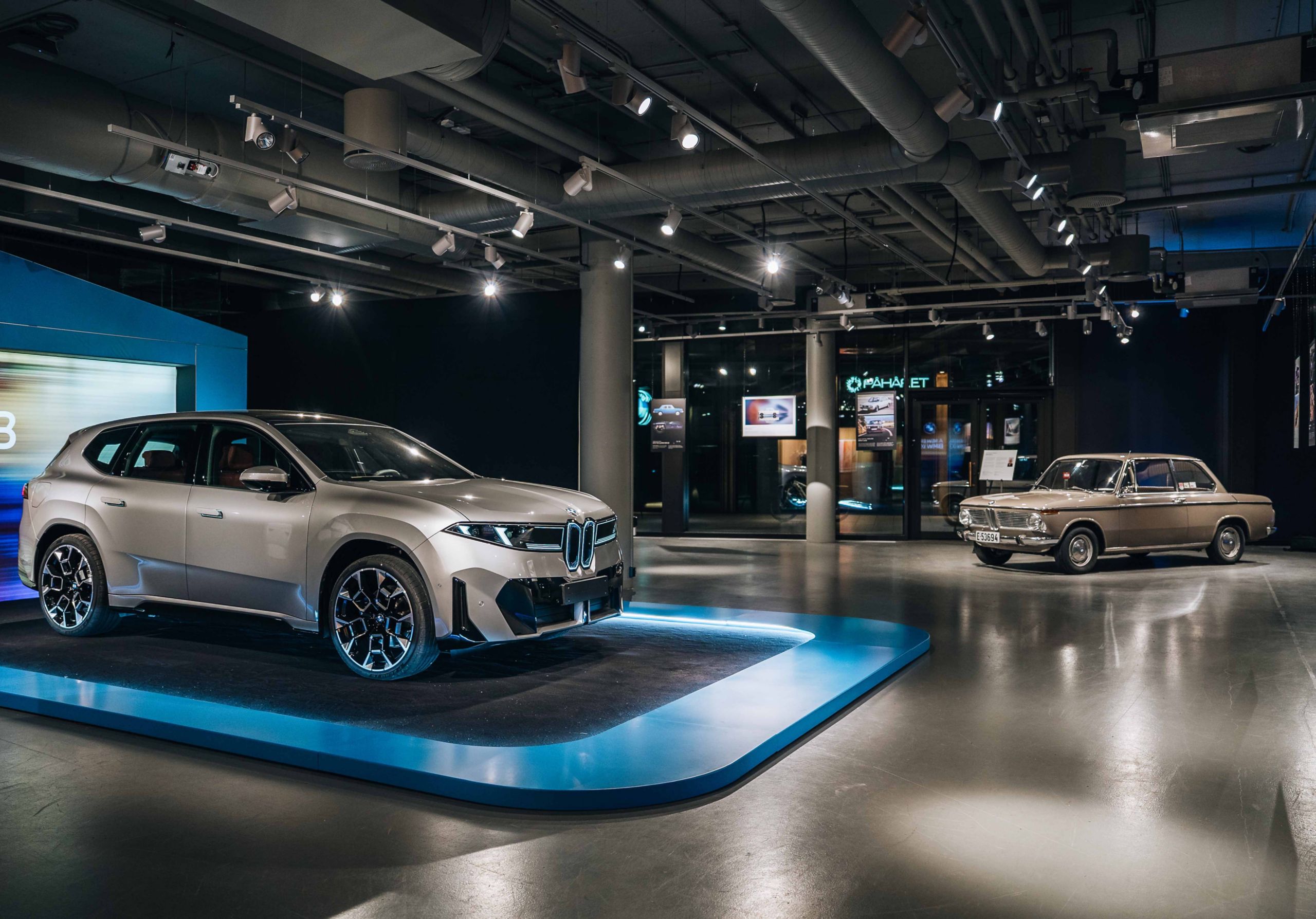 En grå BMW iX3 sedd från sidan, och en beige BMW 1600-2