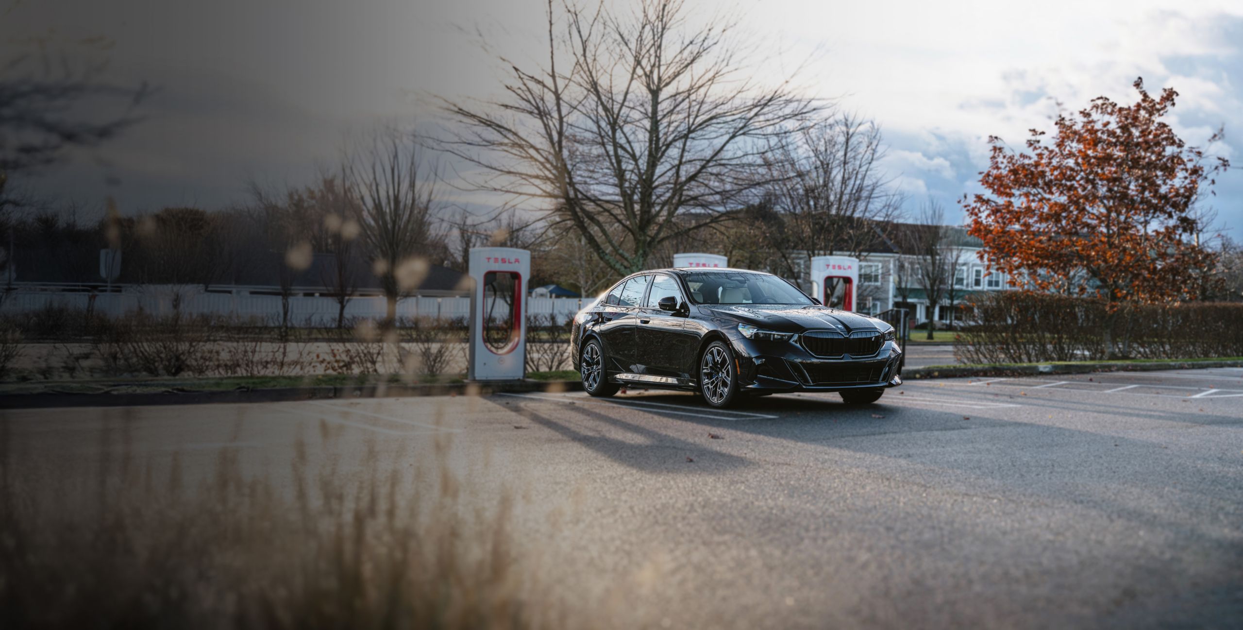 A BMW i5 sedan charges at a Tesla Supercharger station