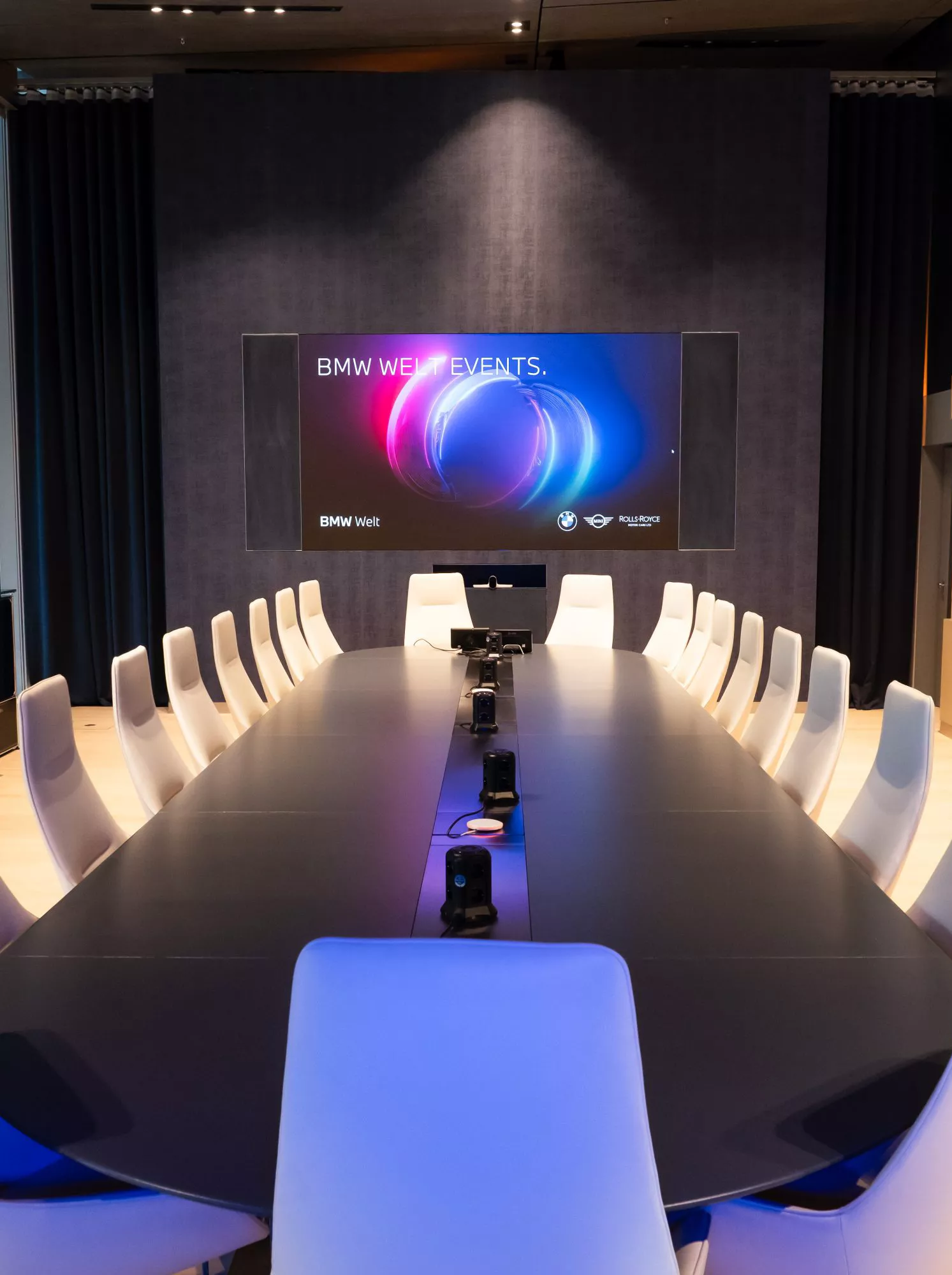 Blick in Konferenzraum mit großem Tisch und weißer Bestuhlung im Business Club der BMW Welt