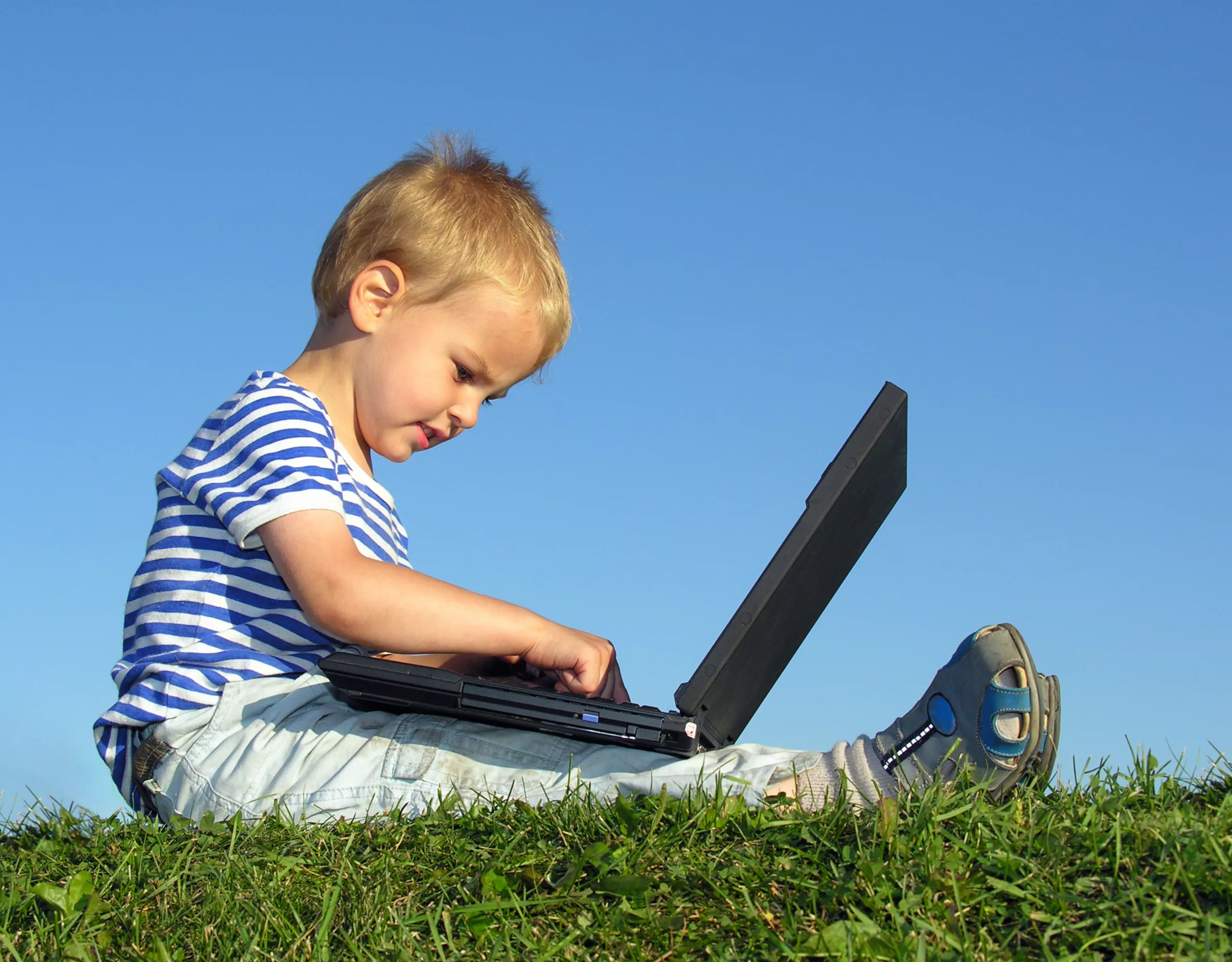 Kind mit Laptop auf Gras