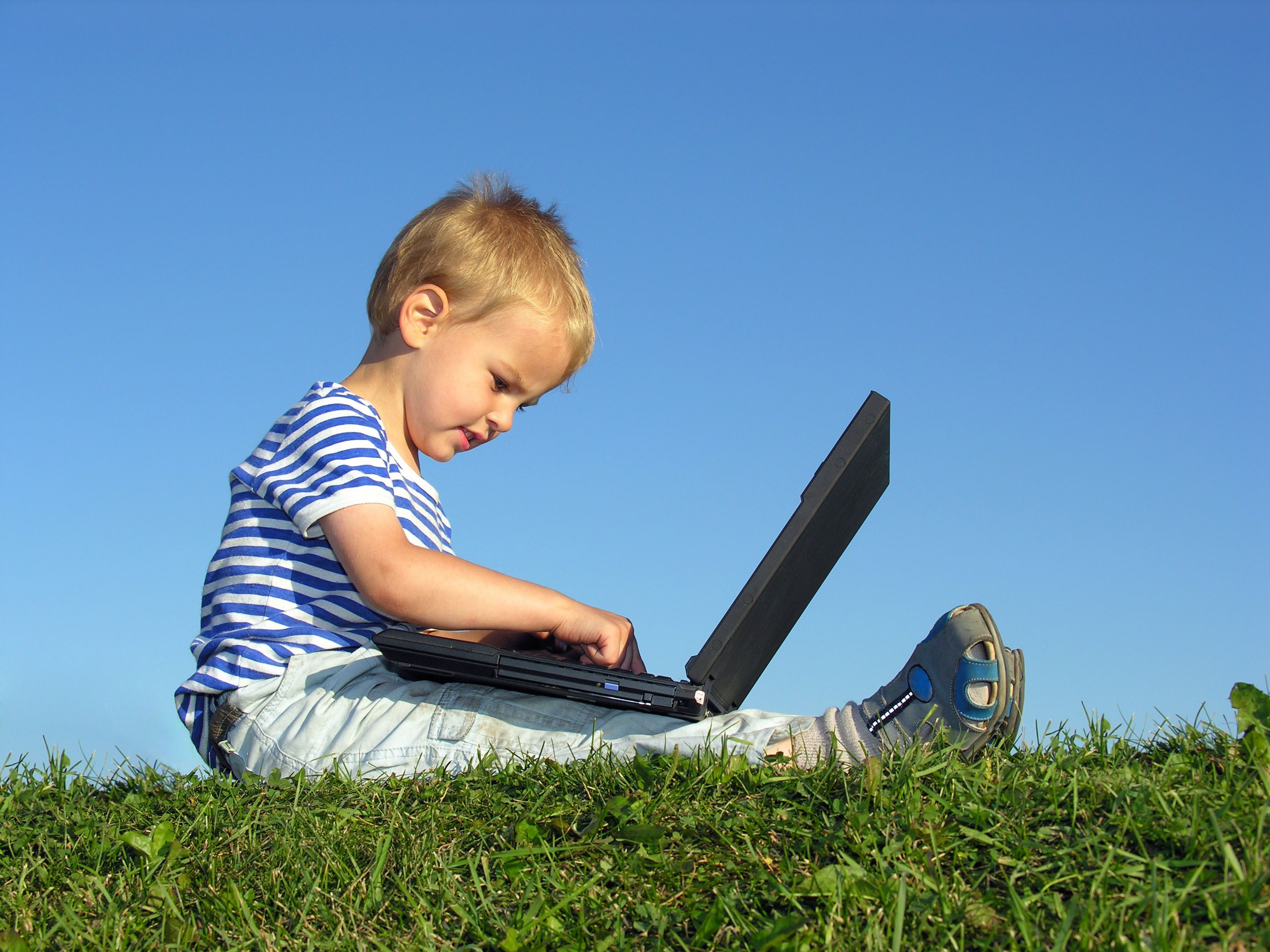 Kind mit Laptop auf Gras