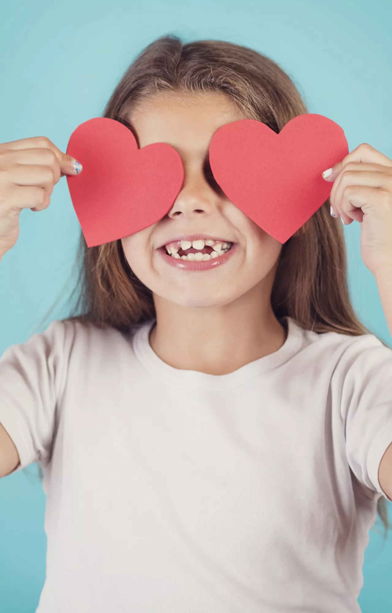 Kind hält rote Herzen vor die Augen
