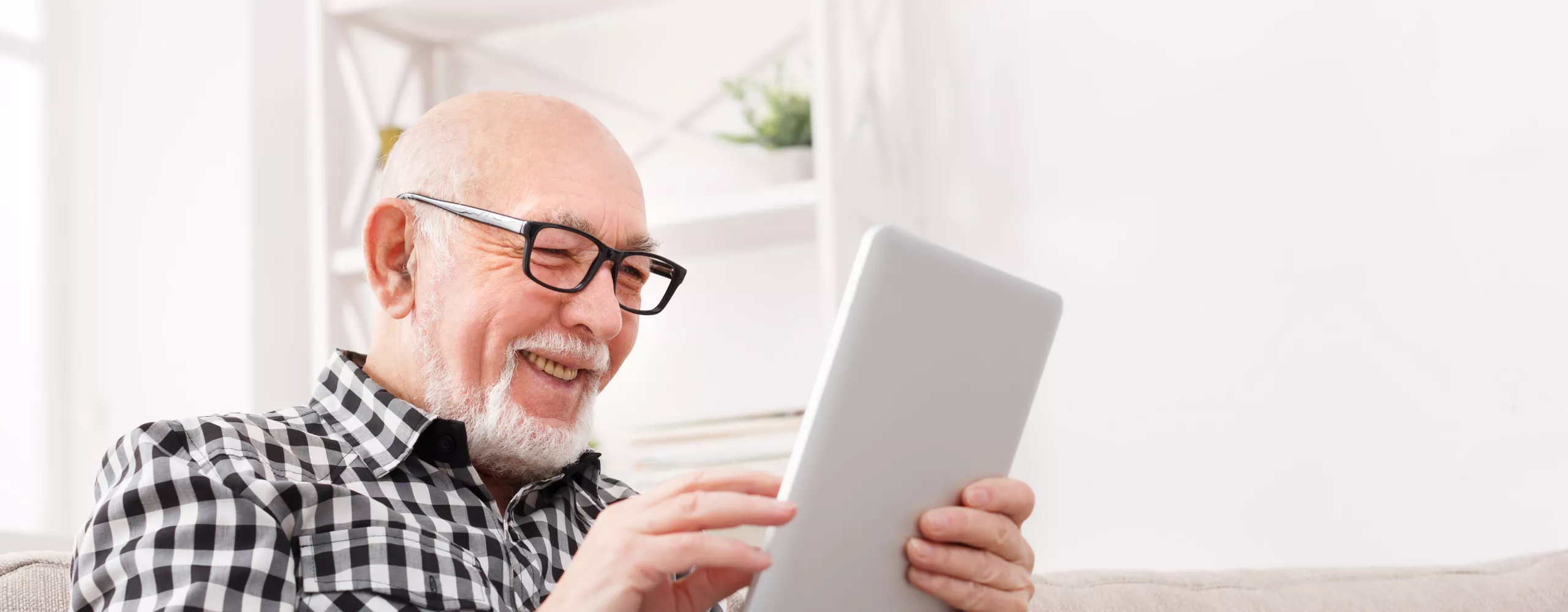 Rentner auf der Couch mit Tablet