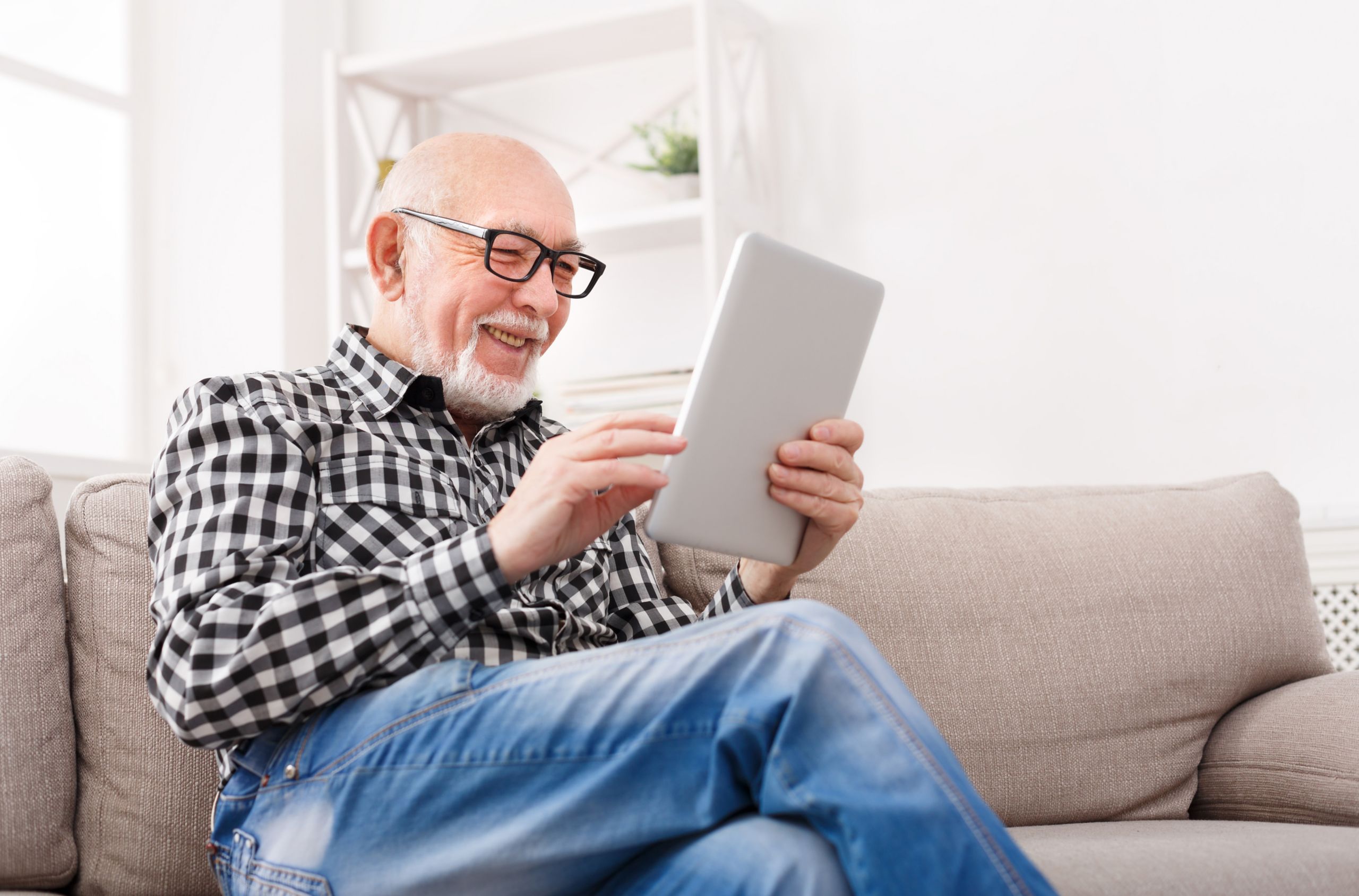 Rentner auf der Couch mit Tablet