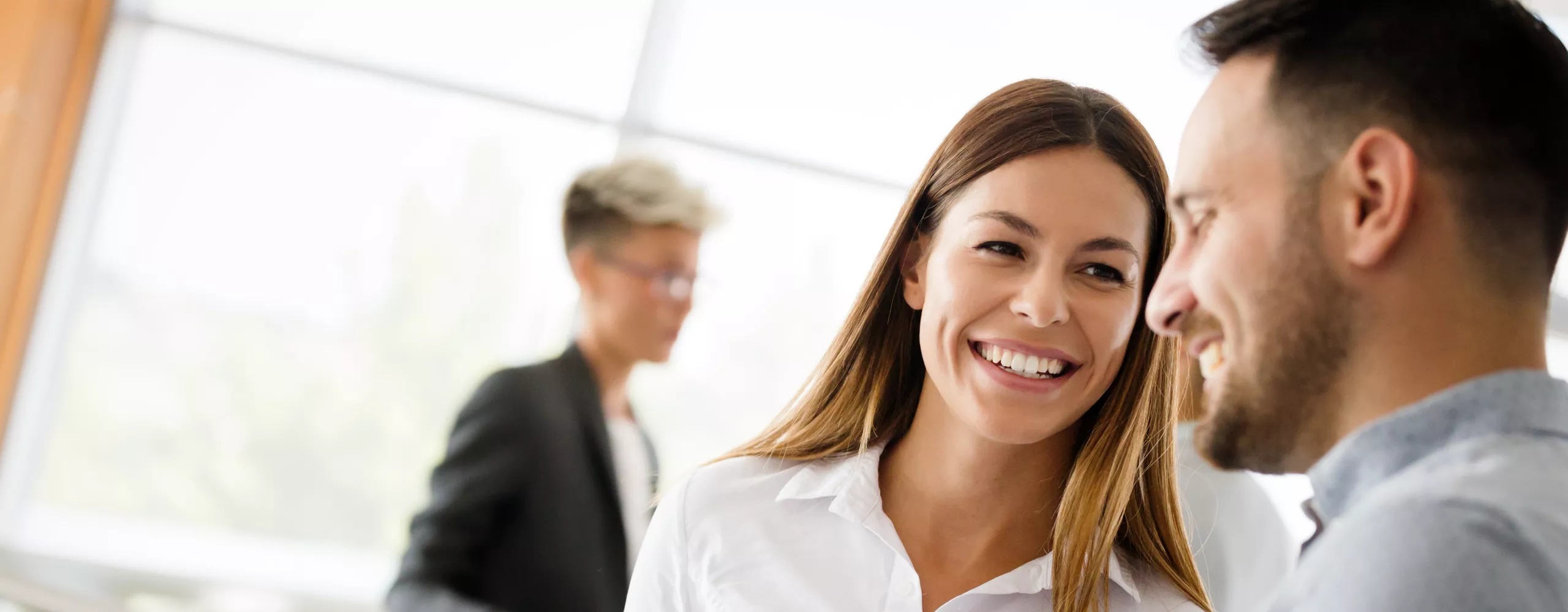 Frau und Mann stehen im Büro und lachen