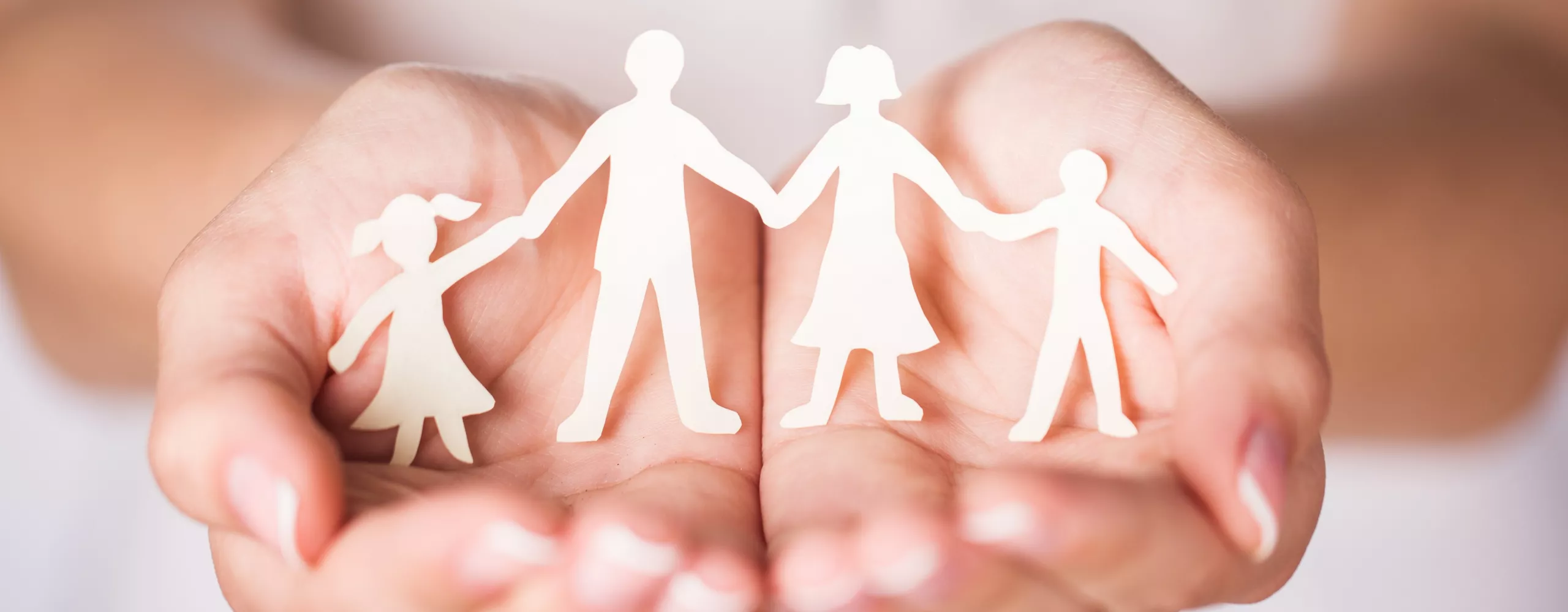 Frau hält Papierfigur von Familie in der Hand