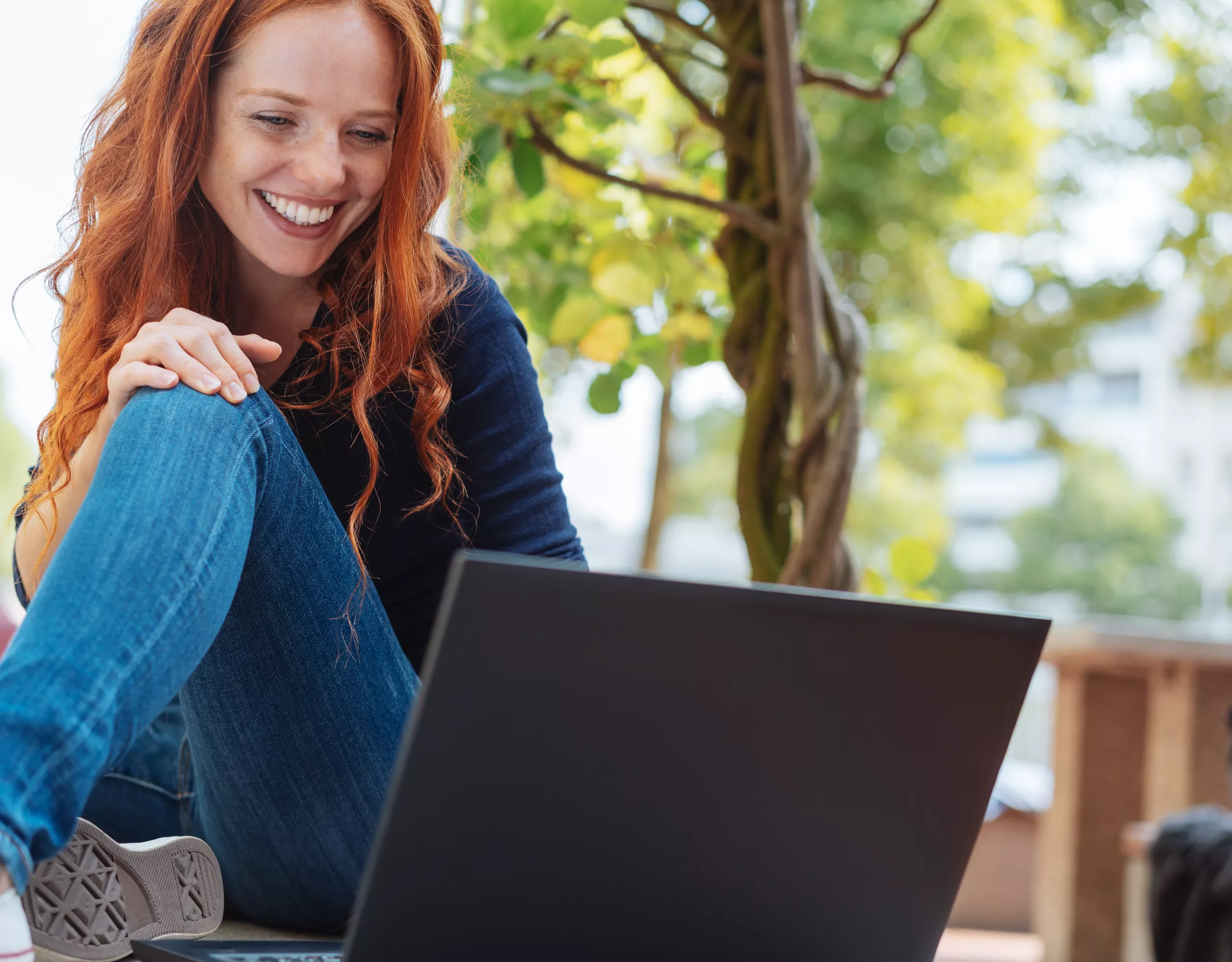 Frau sitzt lächelnd vor Laptop