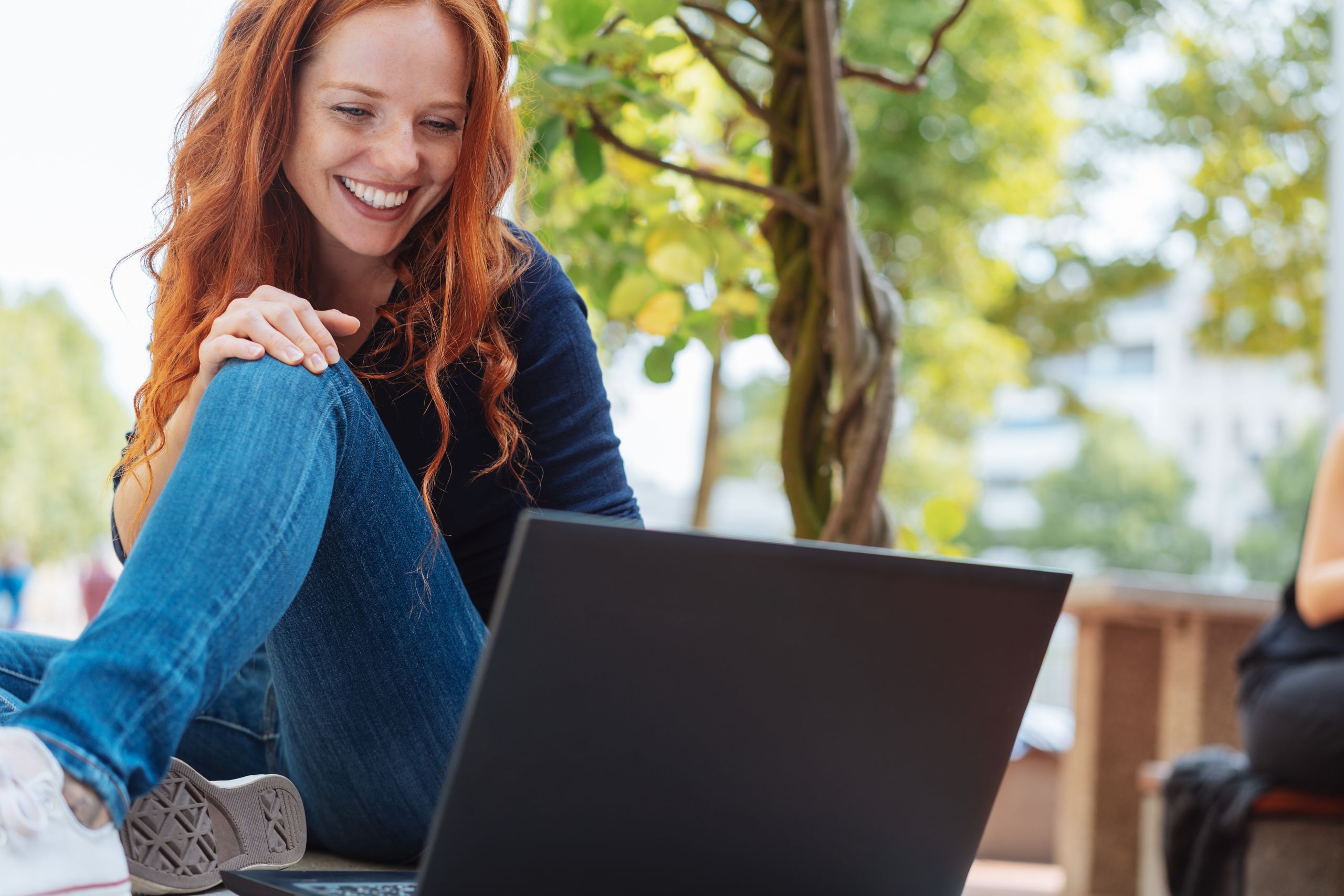 Frau sitzt lächelnd vor Laptop