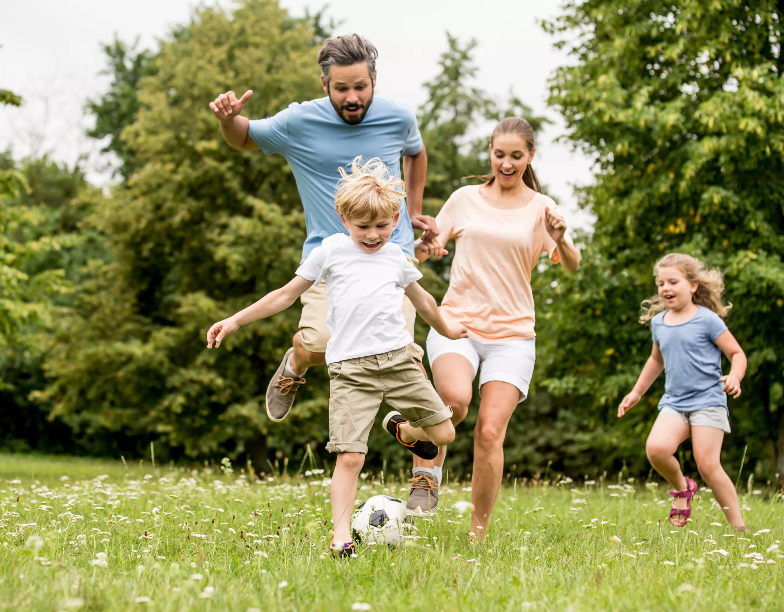 Familie spielt zusammen Fußball auf einer Wiese