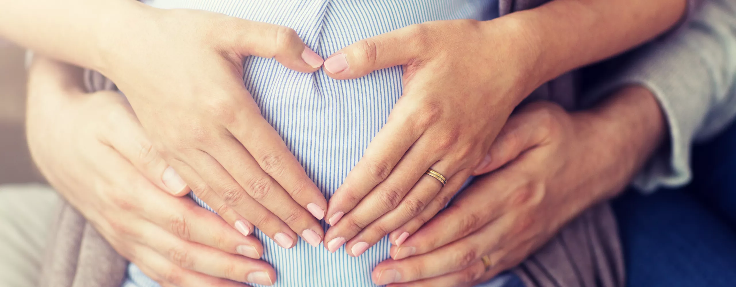 Frau und Mann halten Hände auf den Babybauch