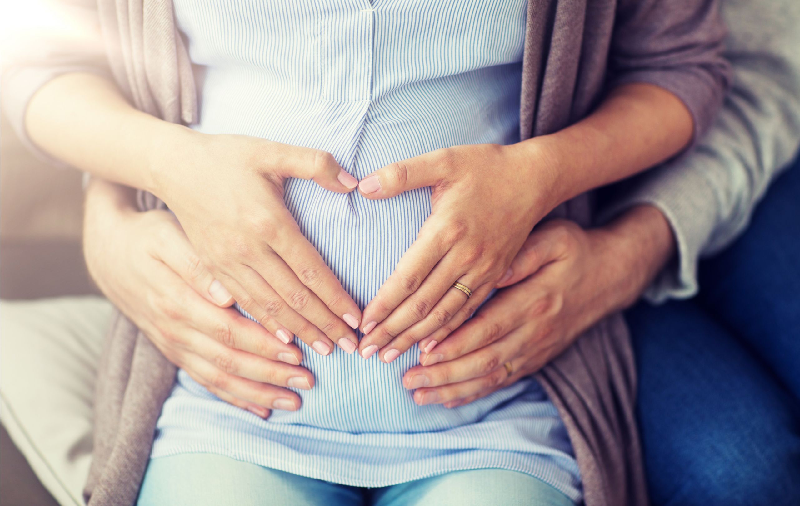 Frau und Mann halten Hände auf den Babybauch