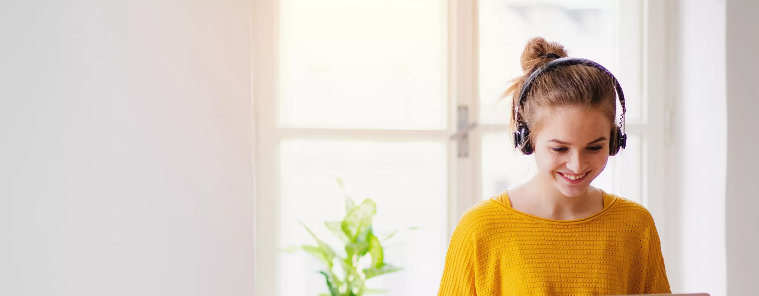 Frau sitzt mit Laptop auf dem Tisch mit Kopfhörern auf