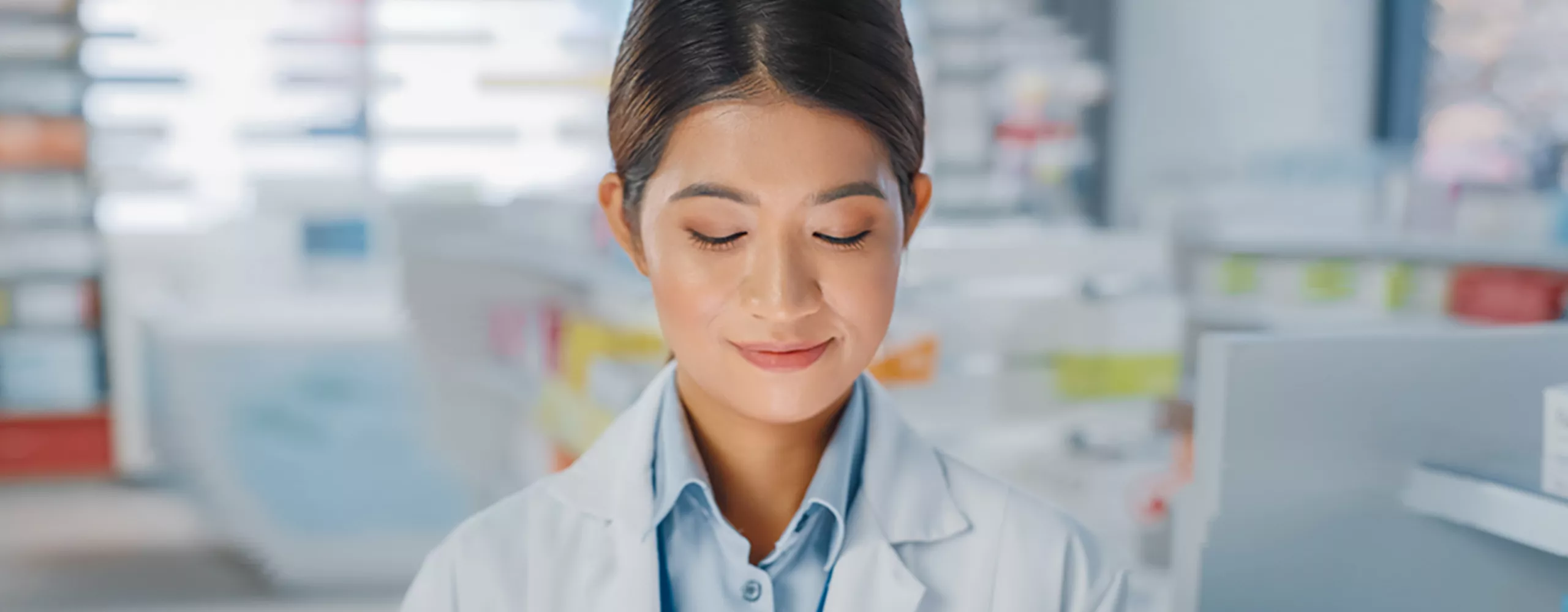 Frau mit weißem Kittel mit Tablet in der Hand in der Apotheke