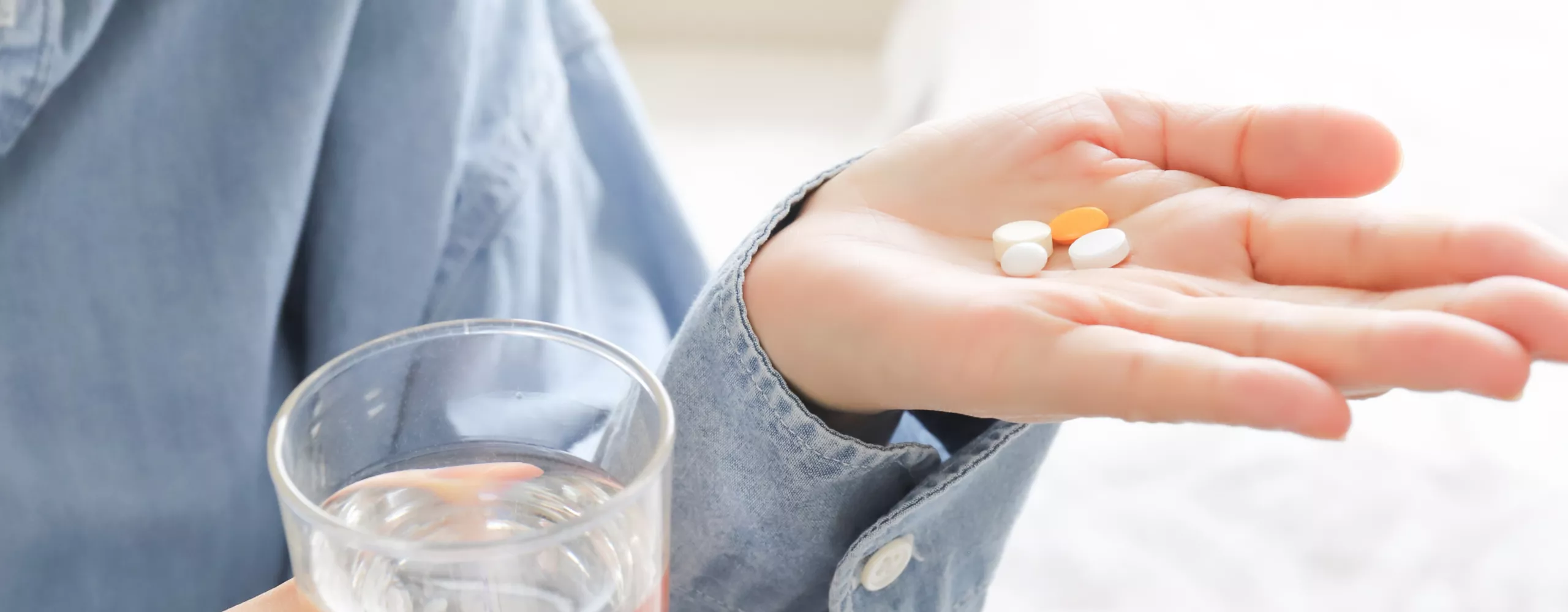Frau nimmt Tabletten mit einem Glas Wasser ein