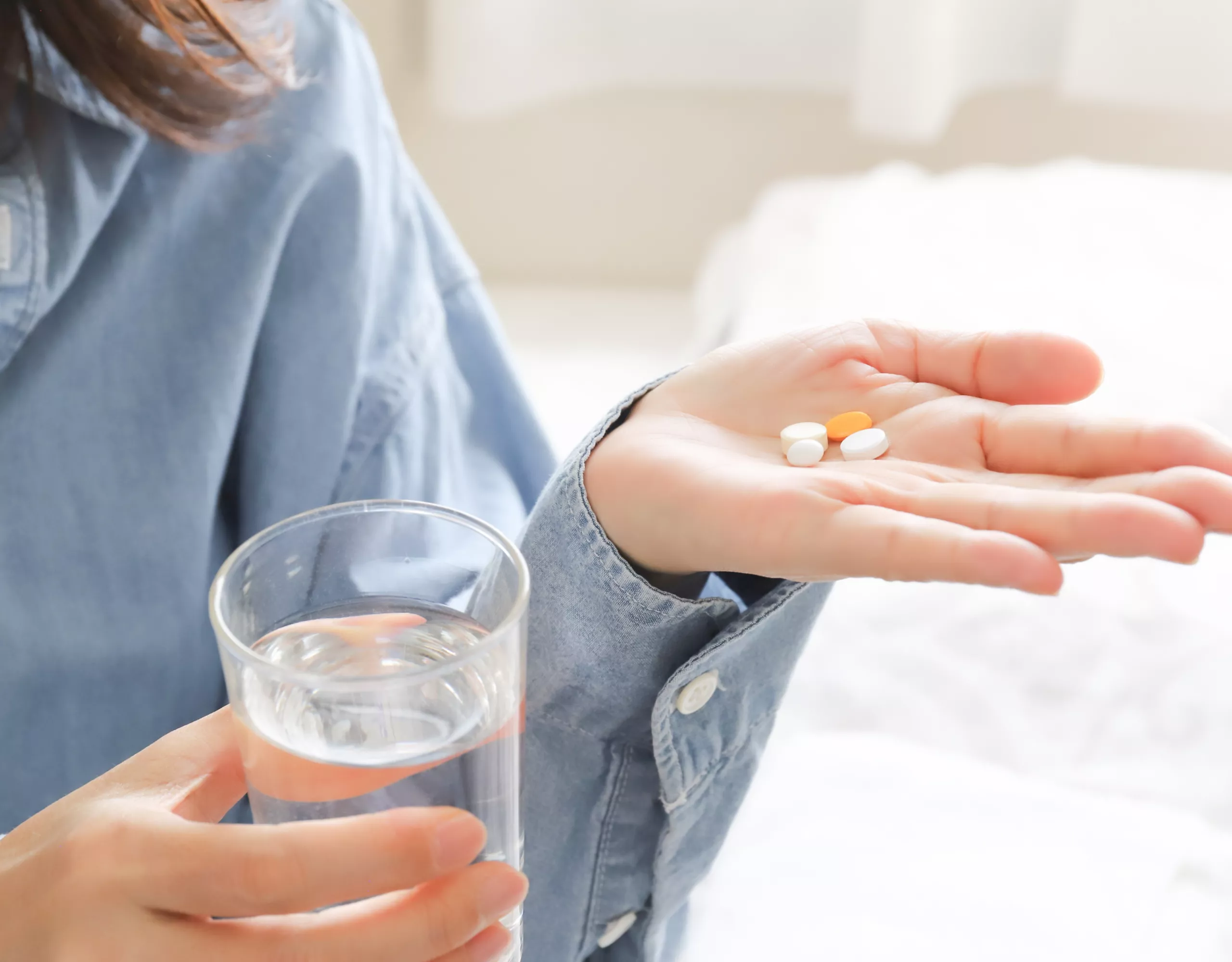 Frau nimmt Tabletten mit einem Glas Wasser ein