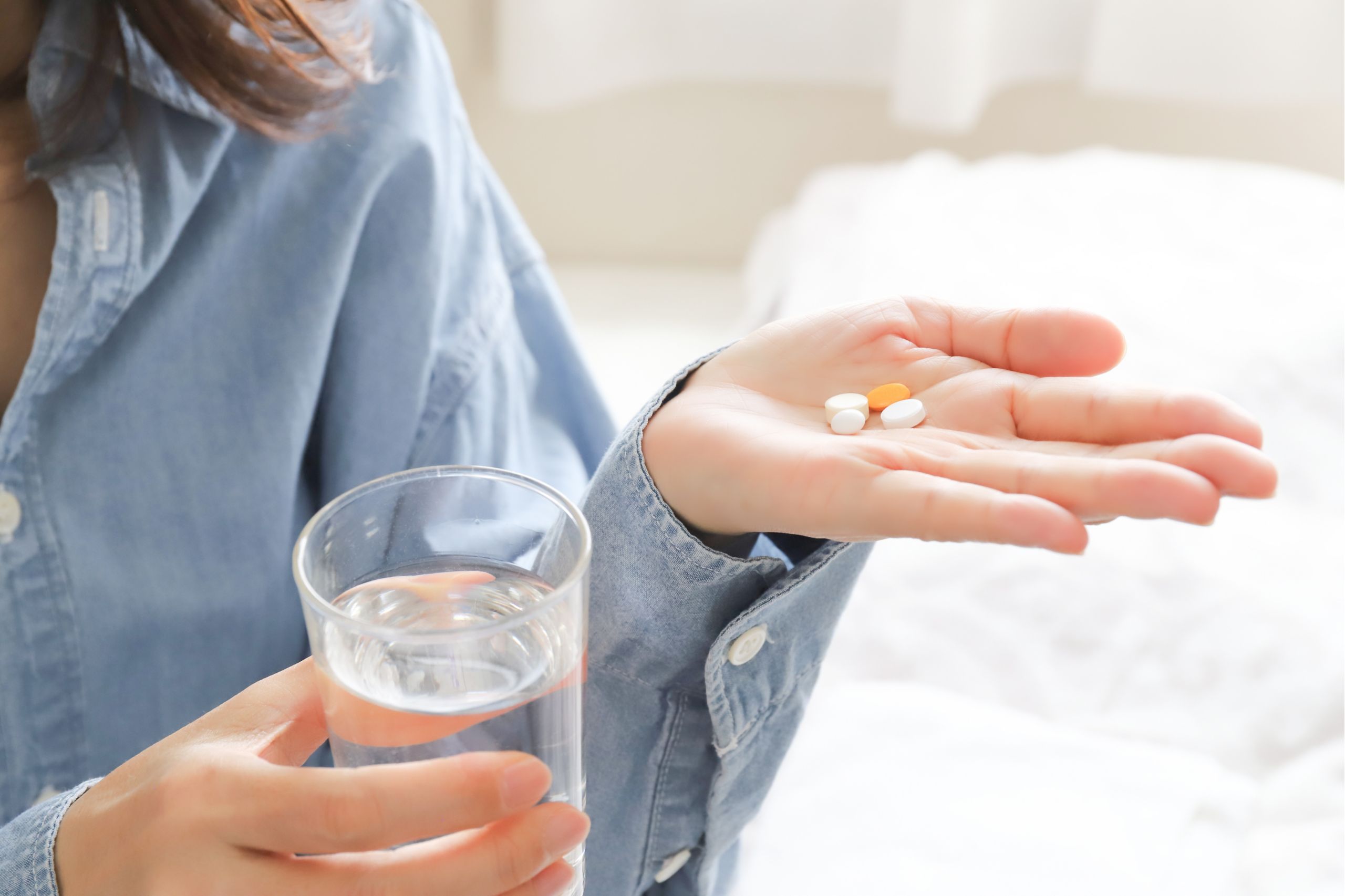 Frau nimmt Tabletten mit einem Glas Wasser ein