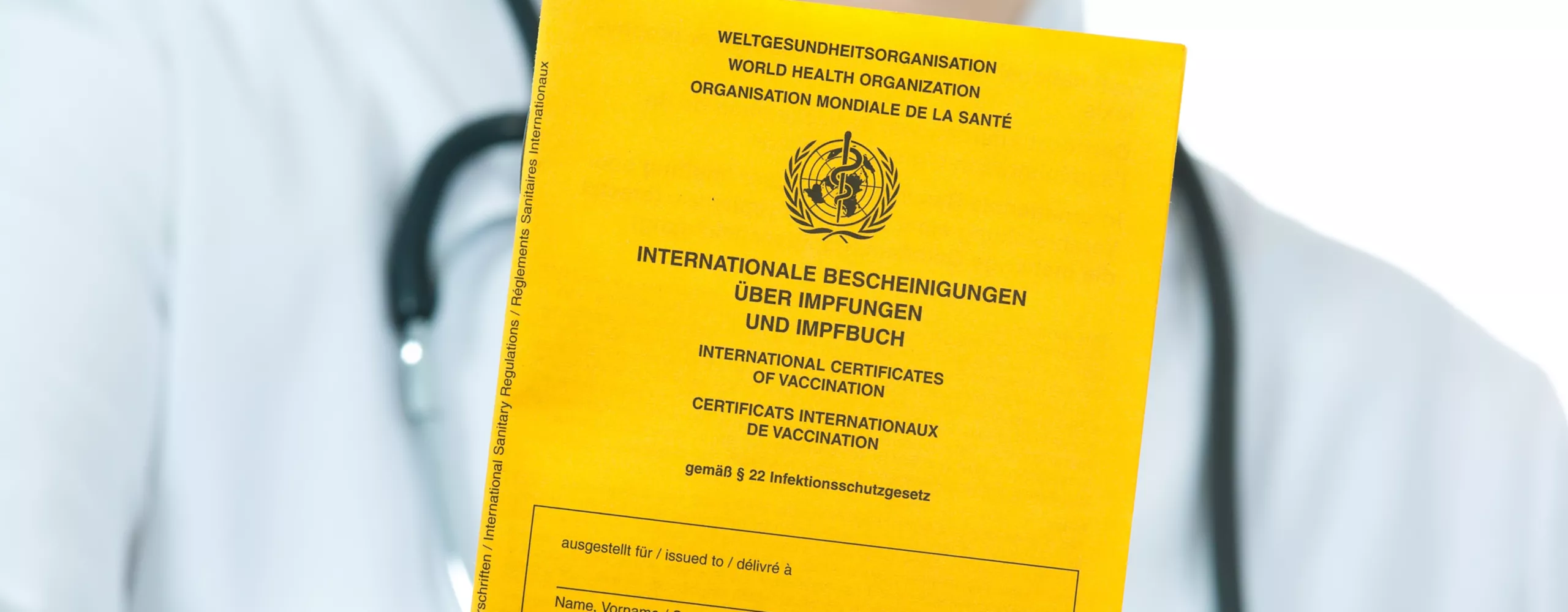 Arzt hält Impfheft in die Kamera.