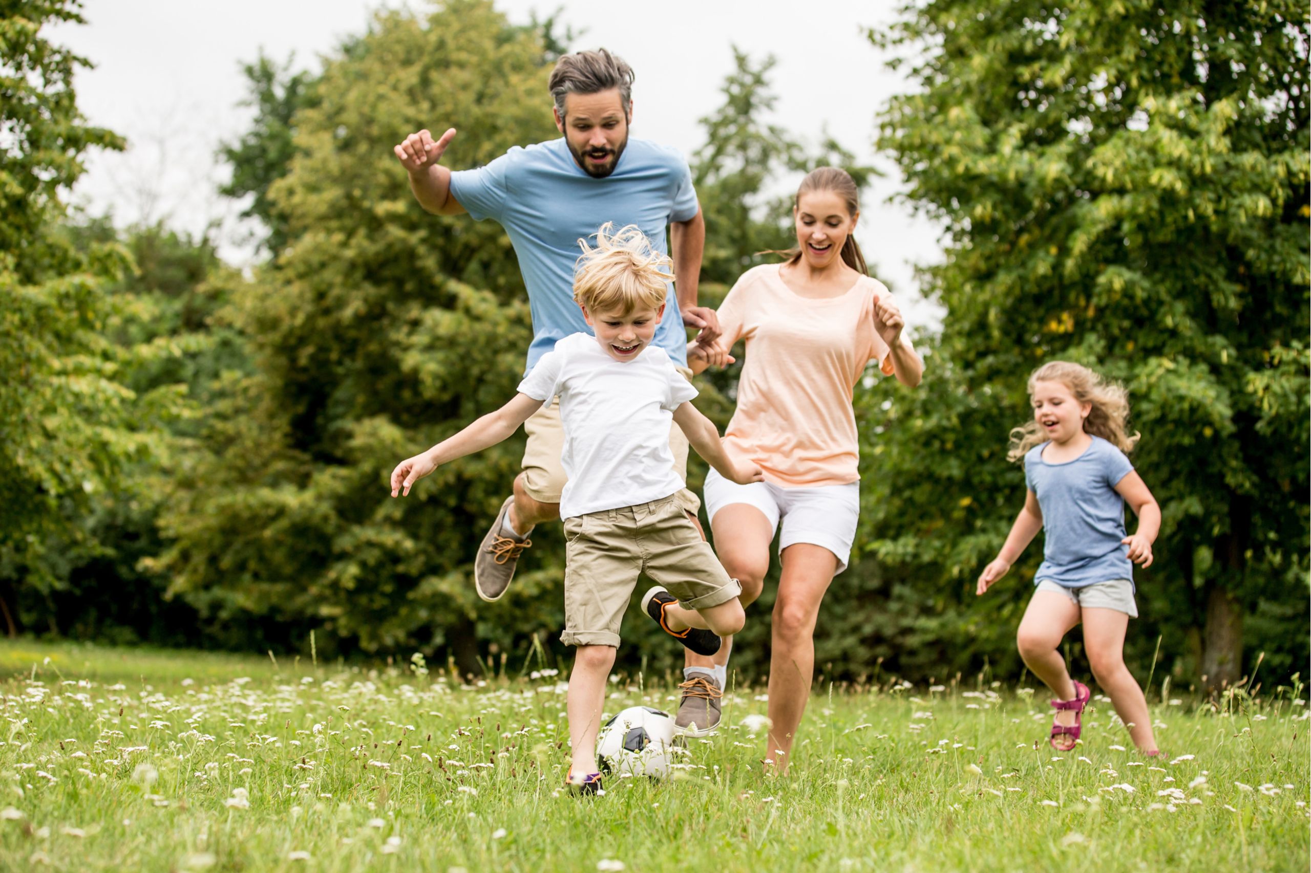 Familie spielt zusammen Fußball auf einer Wiese