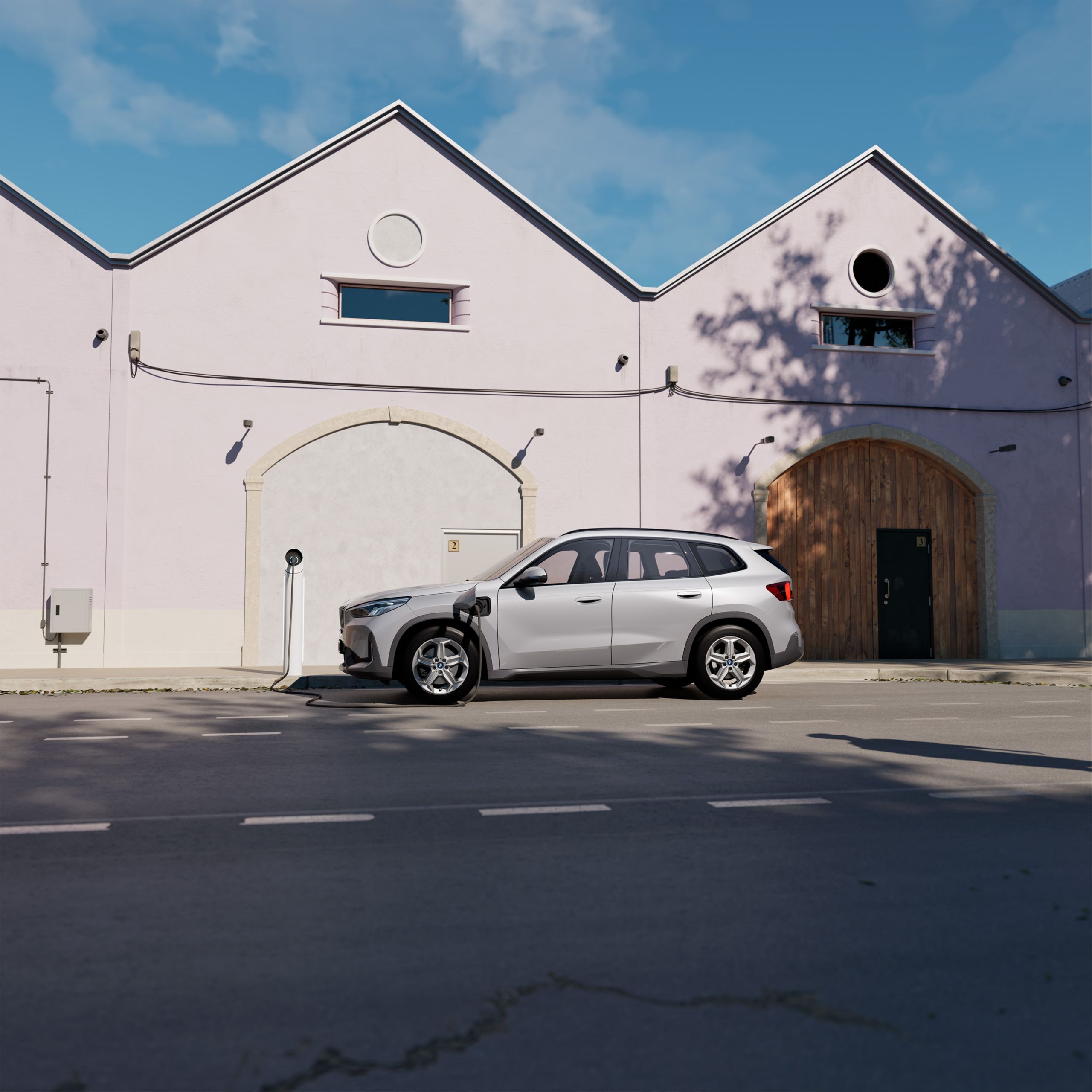 En vit BMW X1 sedd från sidan som är parkerad och laddas 