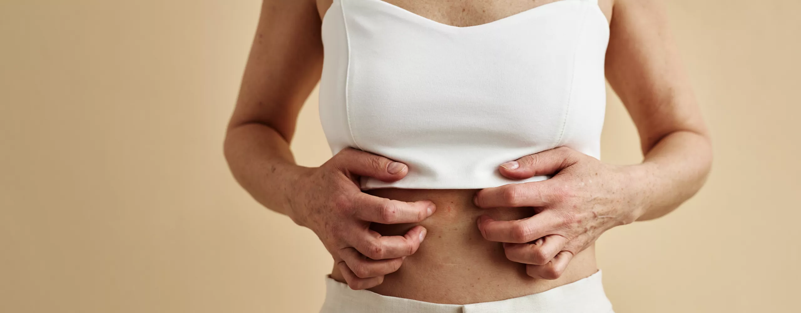 Frau kratzt sich am Bauch mit beiden Händen