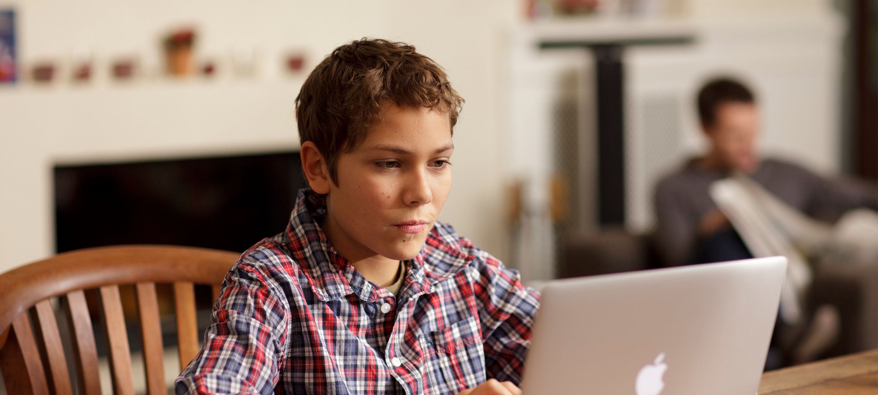 Junge sitzt vor einem Laptop am Tisch