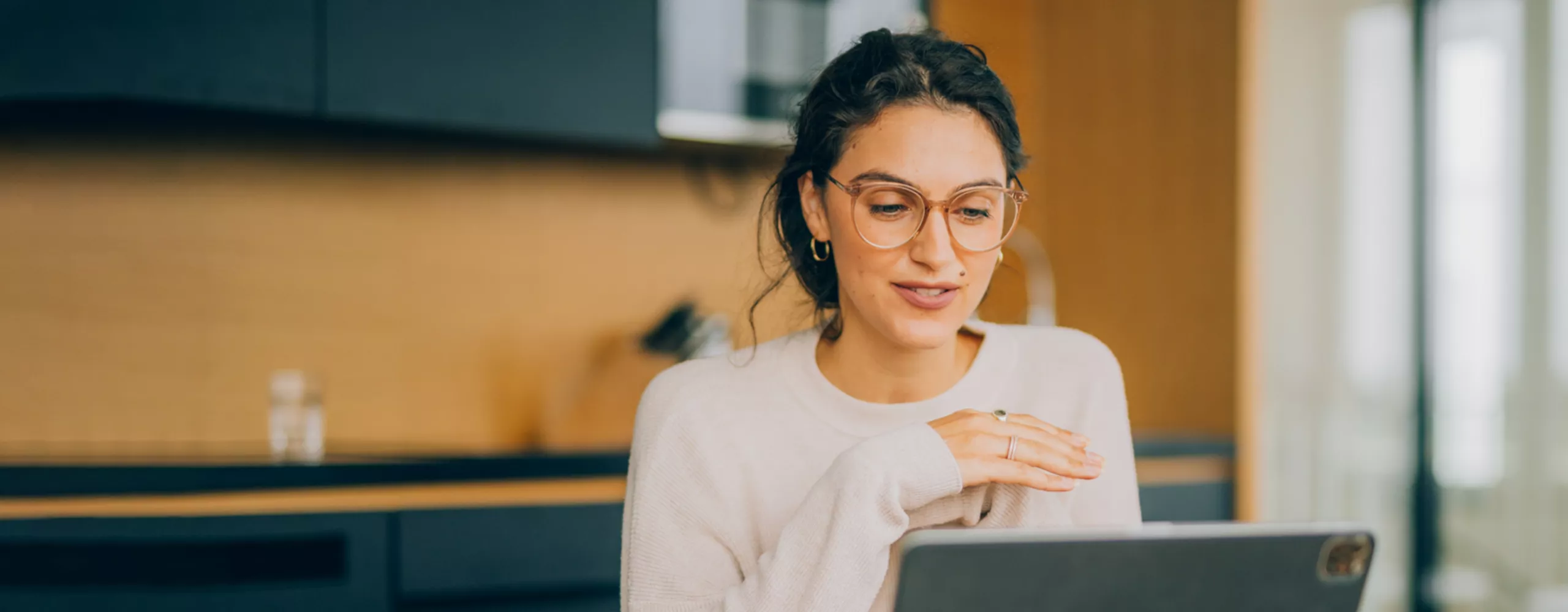 Frau sitzt an einem Tisch und arbeitet am Laptop