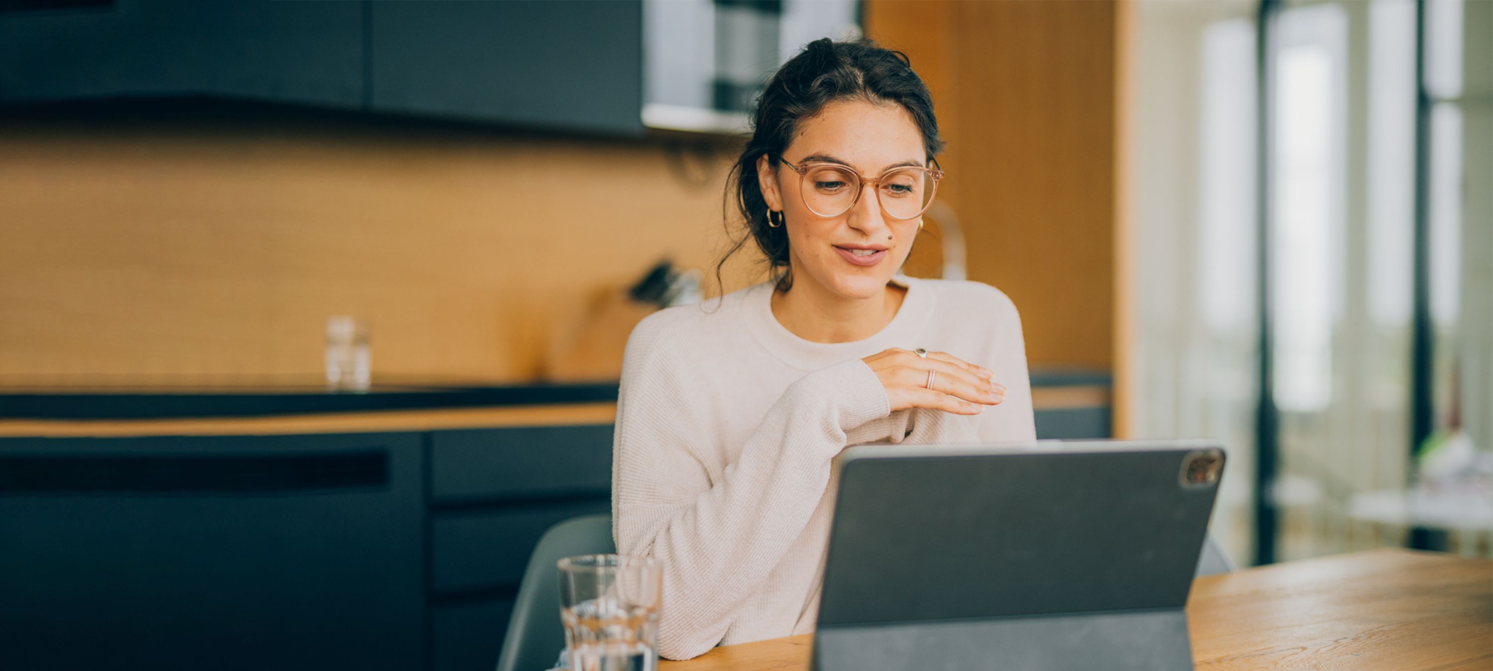 Frau sitzt an einem Tisch und arbeitet am Laptop