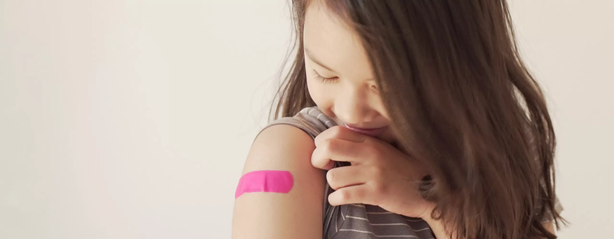 Mädchen hat rosa Pflaster auf dem Arm 