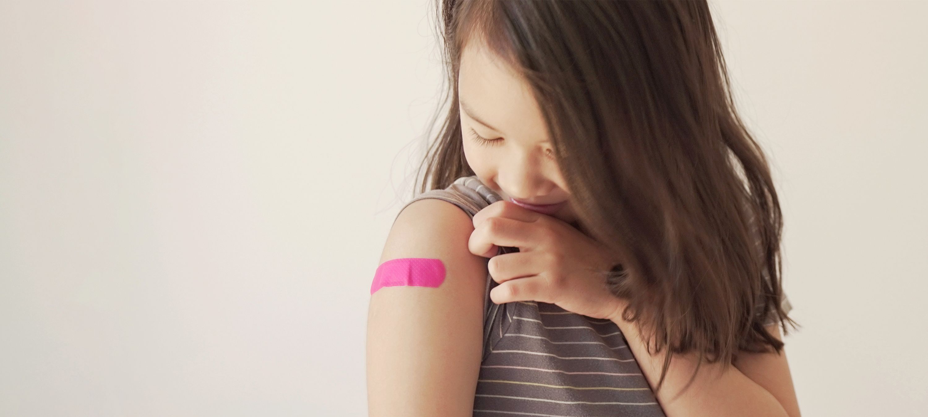 Mädchen hat rosa Pflaster auf dem Arm 