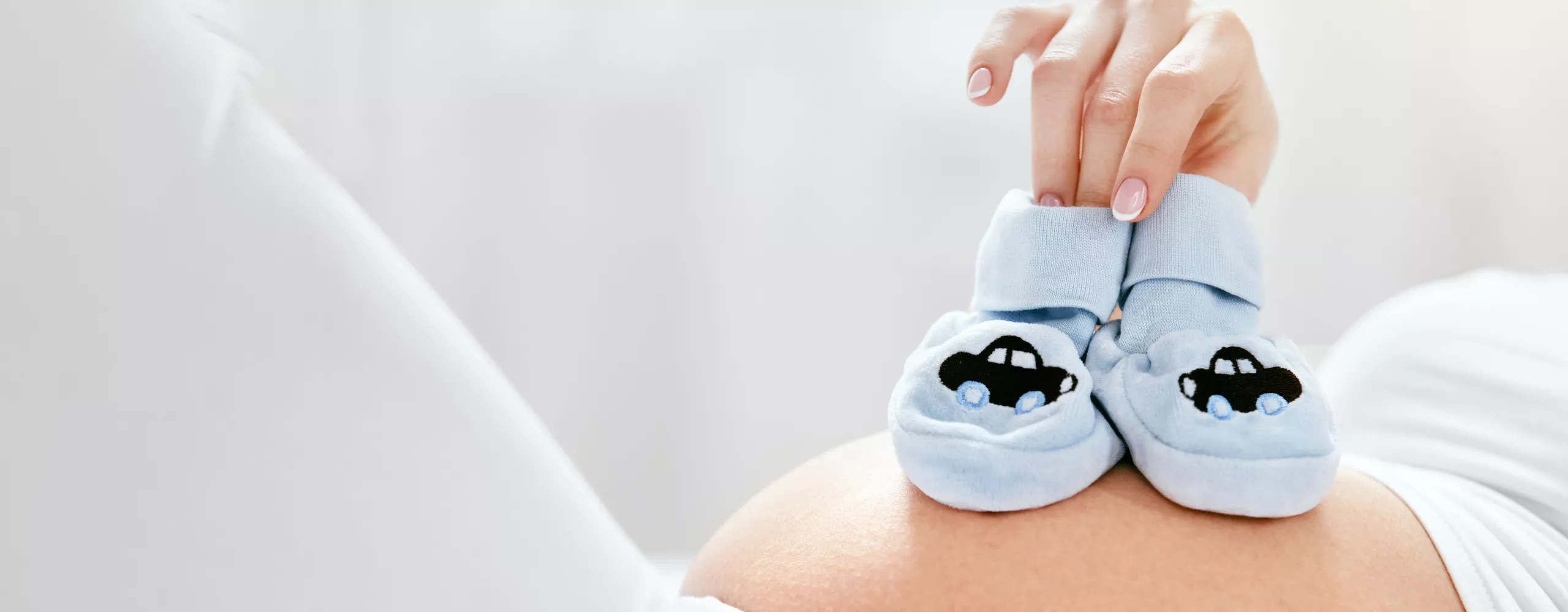 Schwangere Frau hat Babyschuhe auf dem Bauch