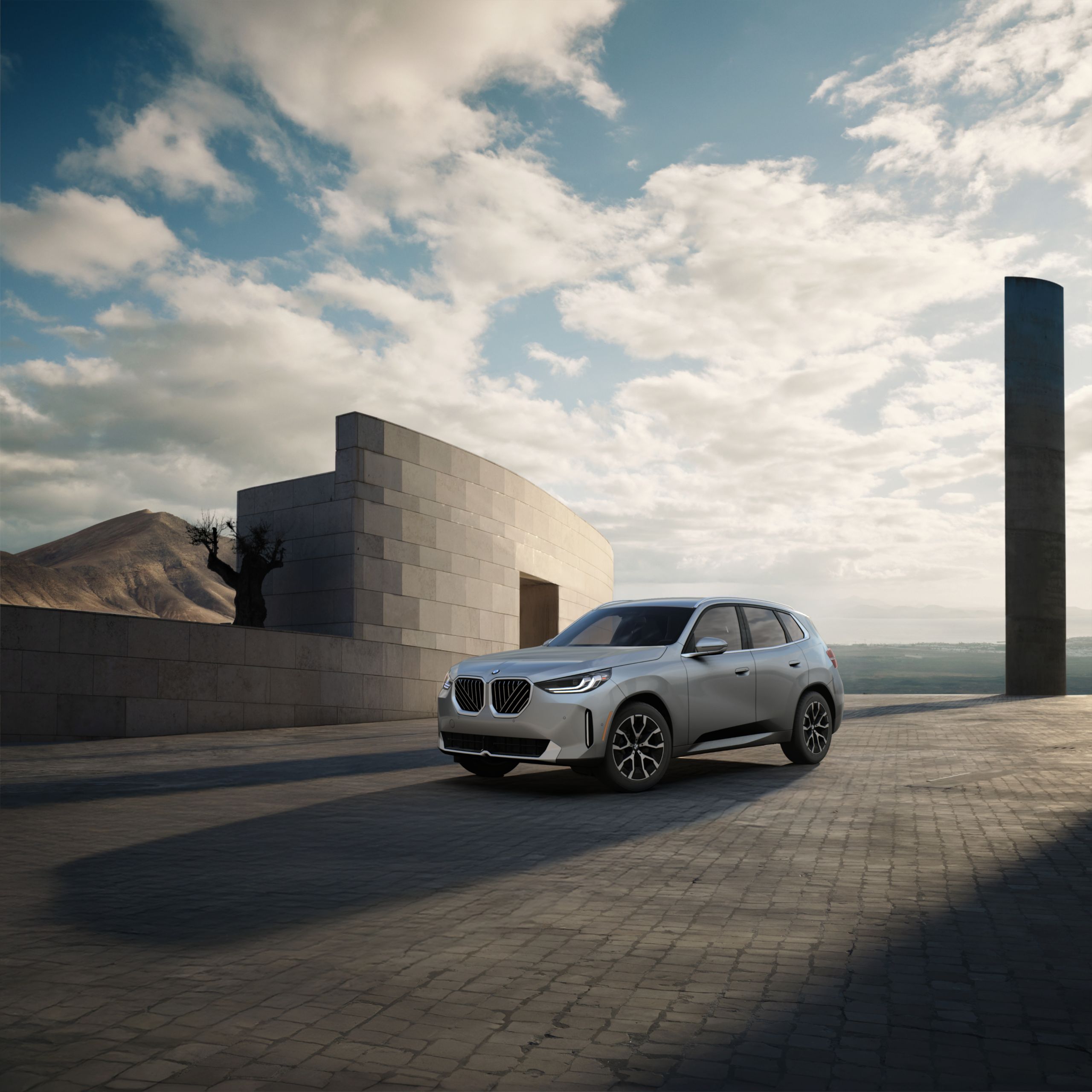 The X3 30 xDrive parked on an open cobblestone structure in front of the ocean.