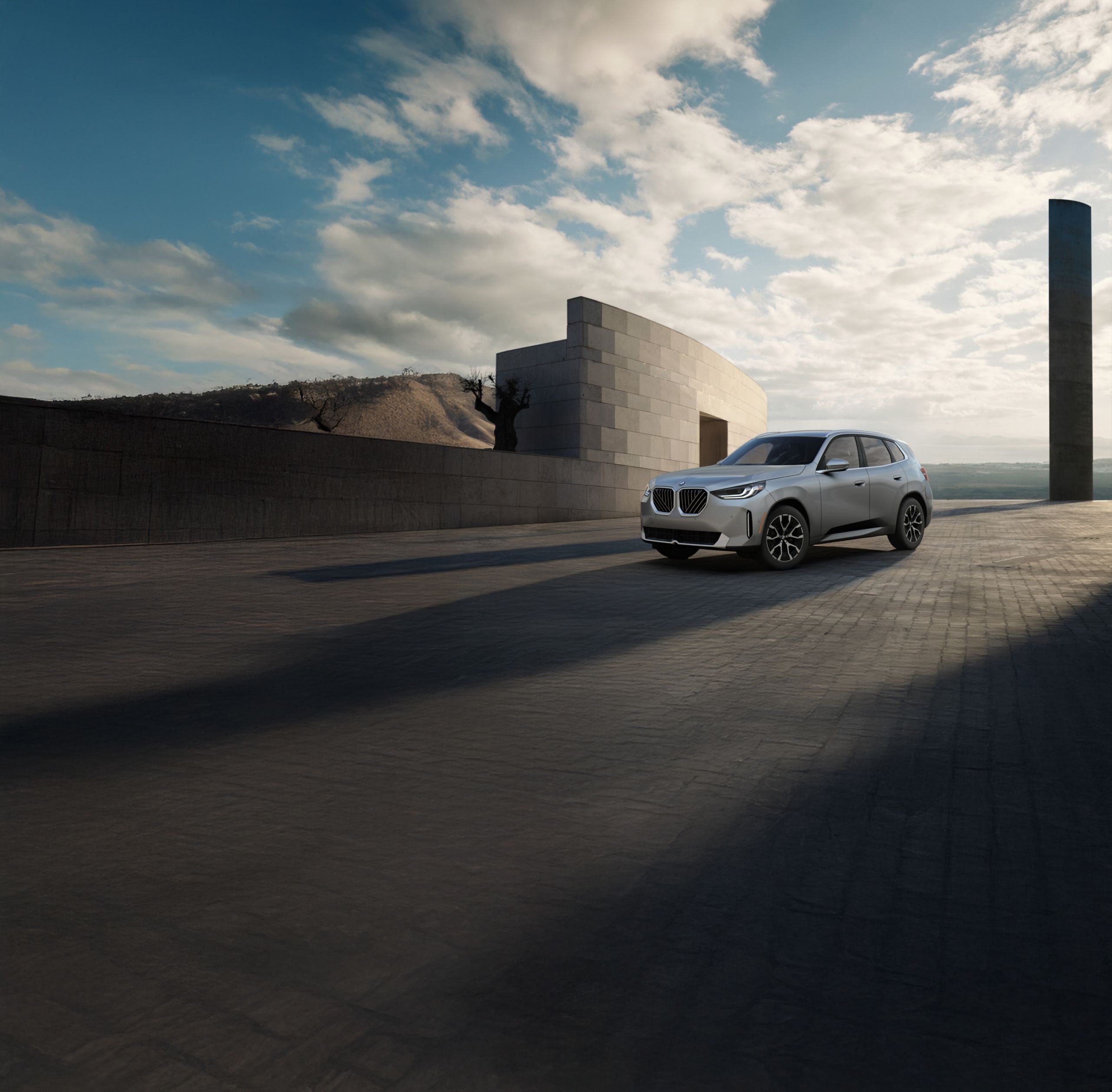 The X3 30 xDrive parked on an open cobblestone structure in front of the ocean.