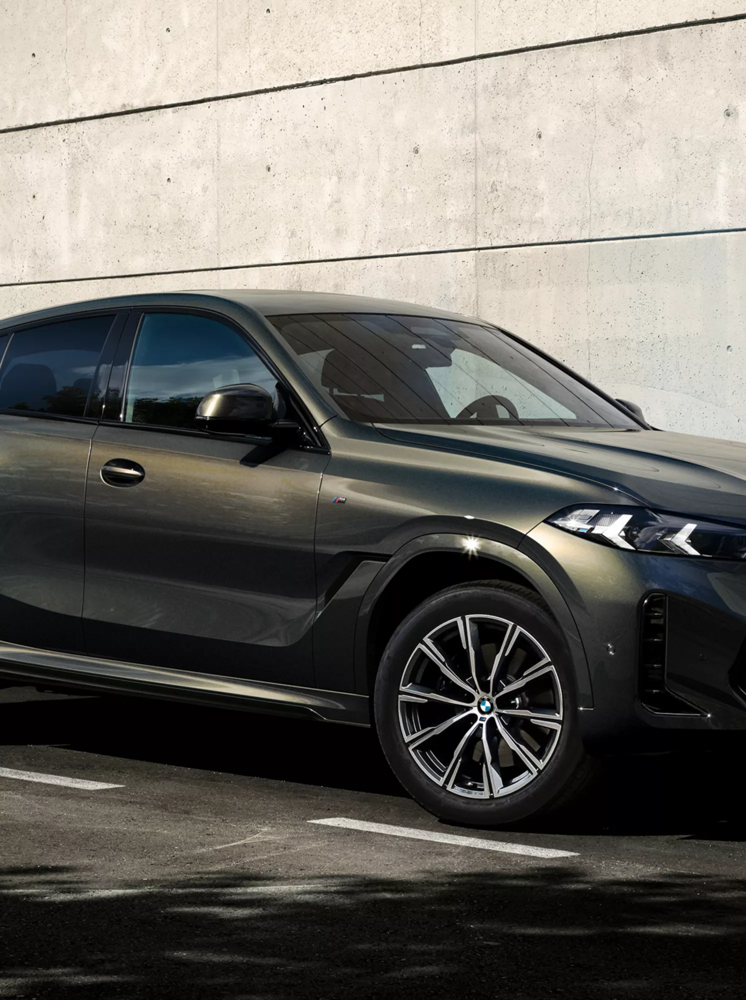モダンな建物の前に停められたBMW X6とその横を歩く男性