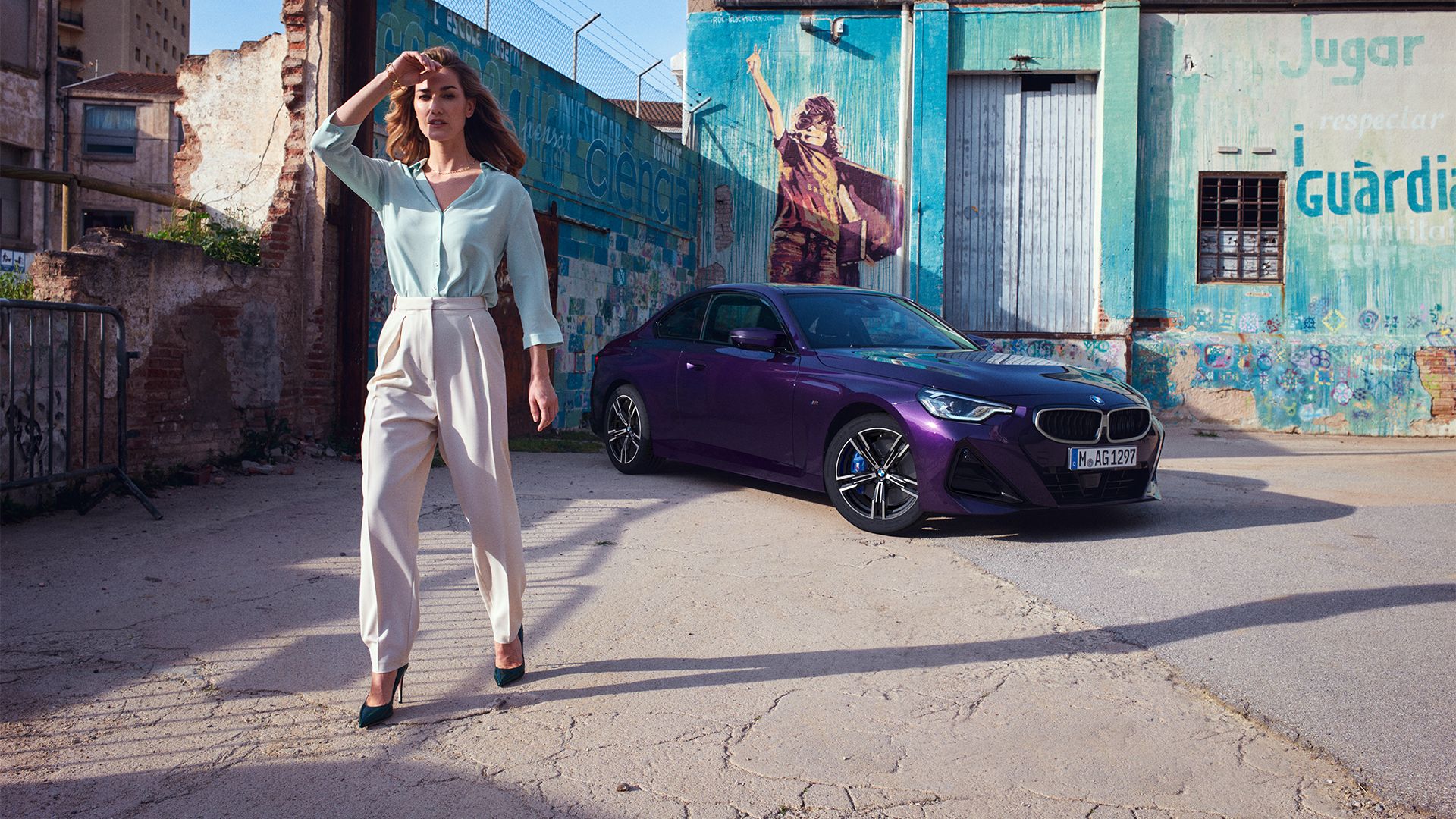 Eine Frau steht vor einem violetten BMW 2er Coupé