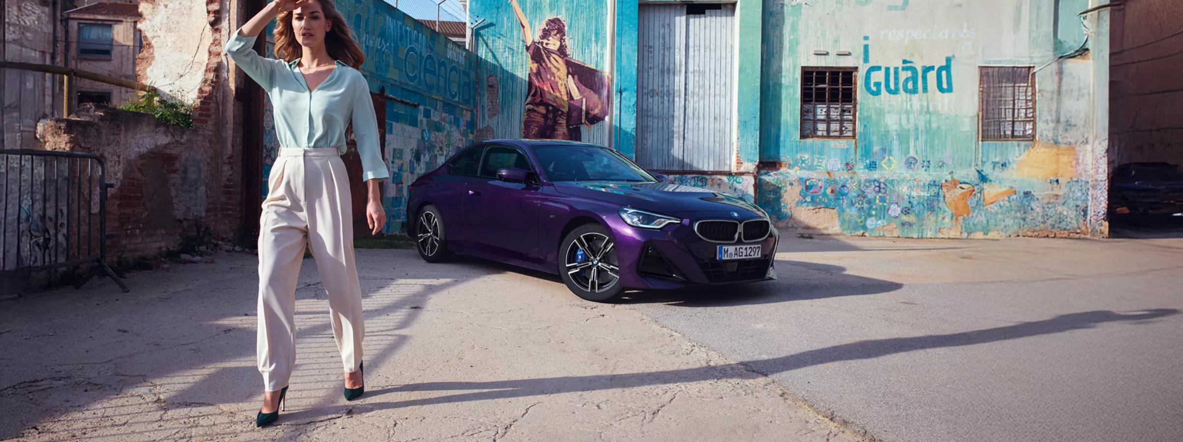 Eine Frau steht vor einem violetten BMW 2er Coupé