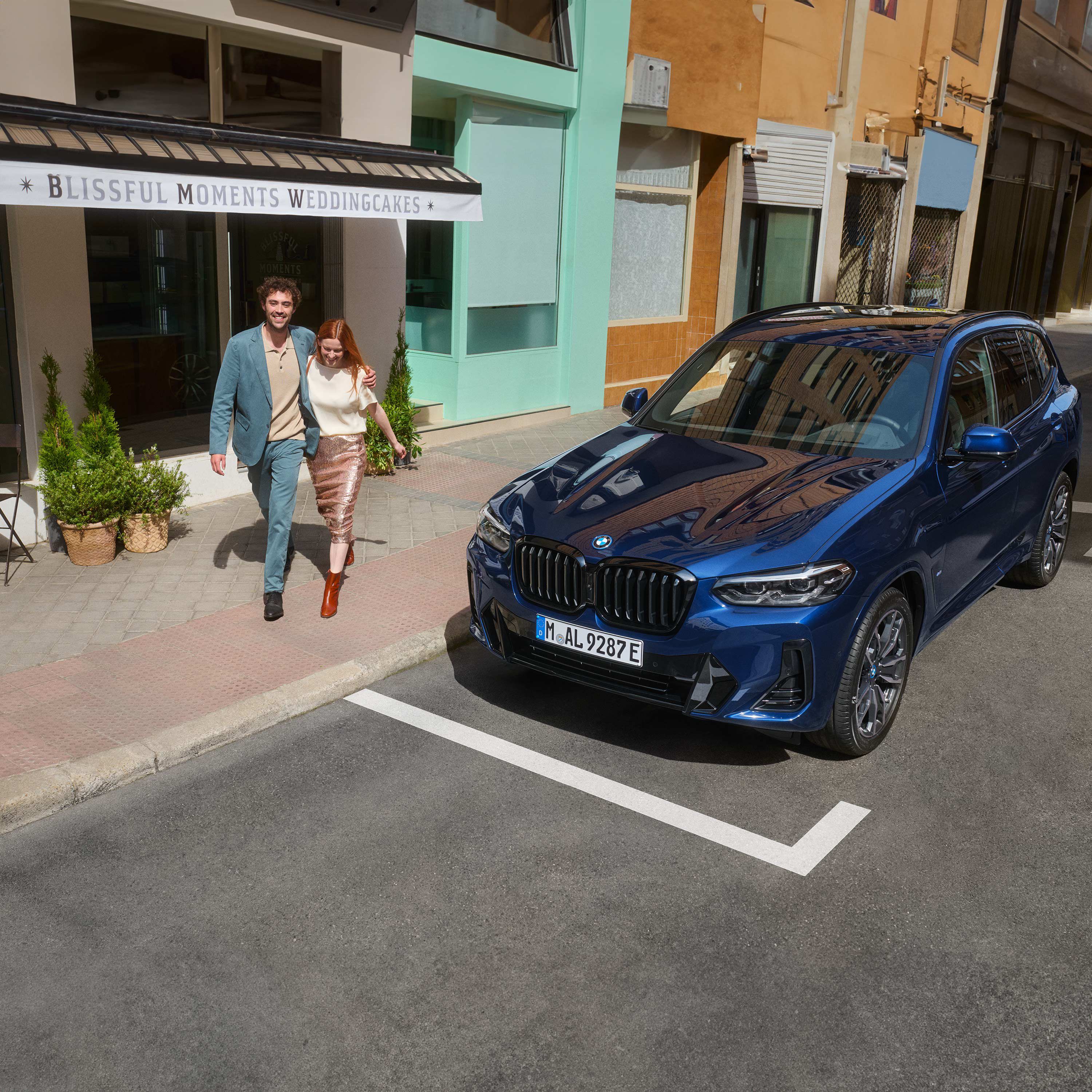 Coppia che si abbraccia e cammina davanti a una BMW.