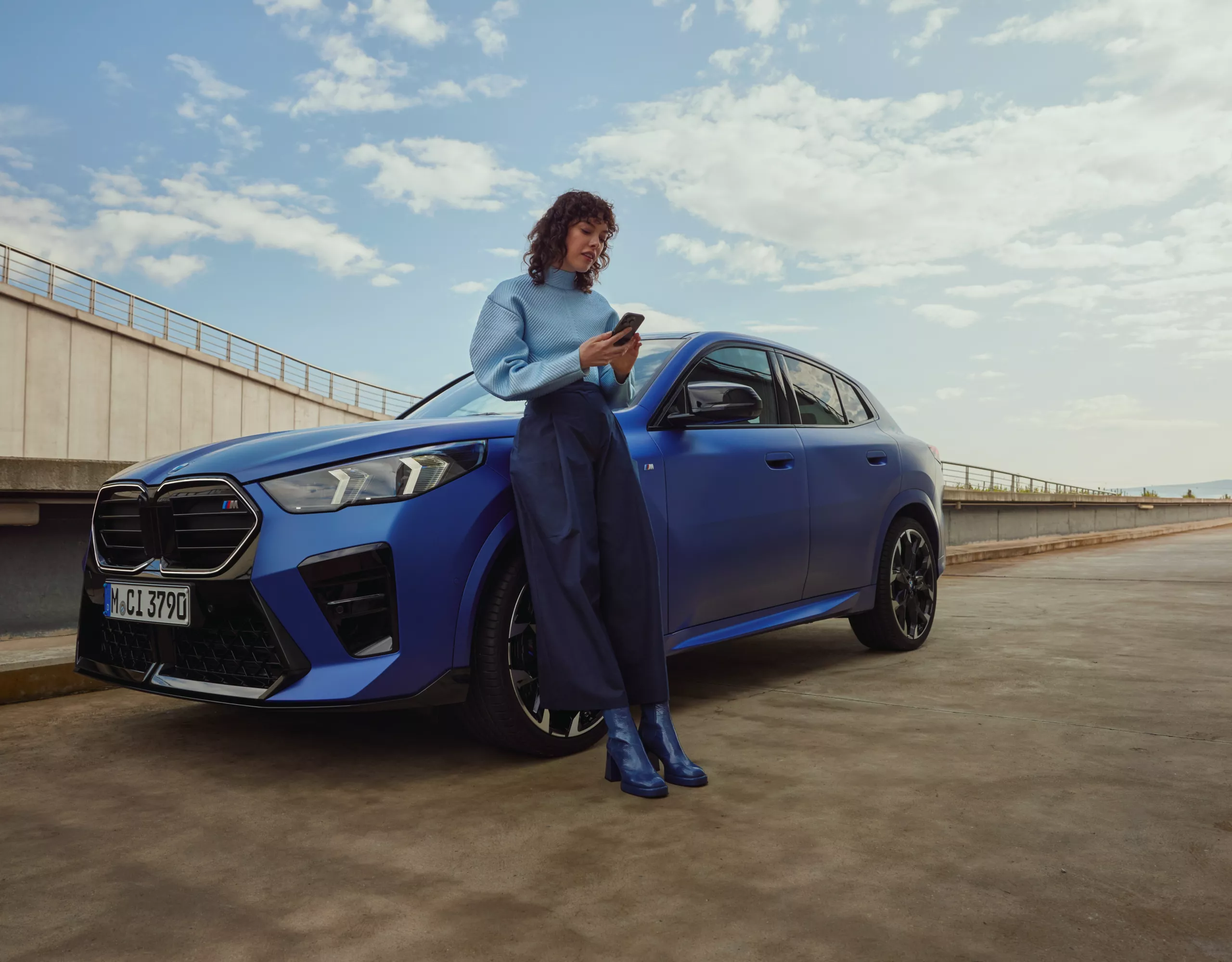 A man is approaching a BMW X2. Around the vehicle, the 3 phases of the digital key featuring the welcome light, unlocking of the doors and engine start are embedded in an overlay