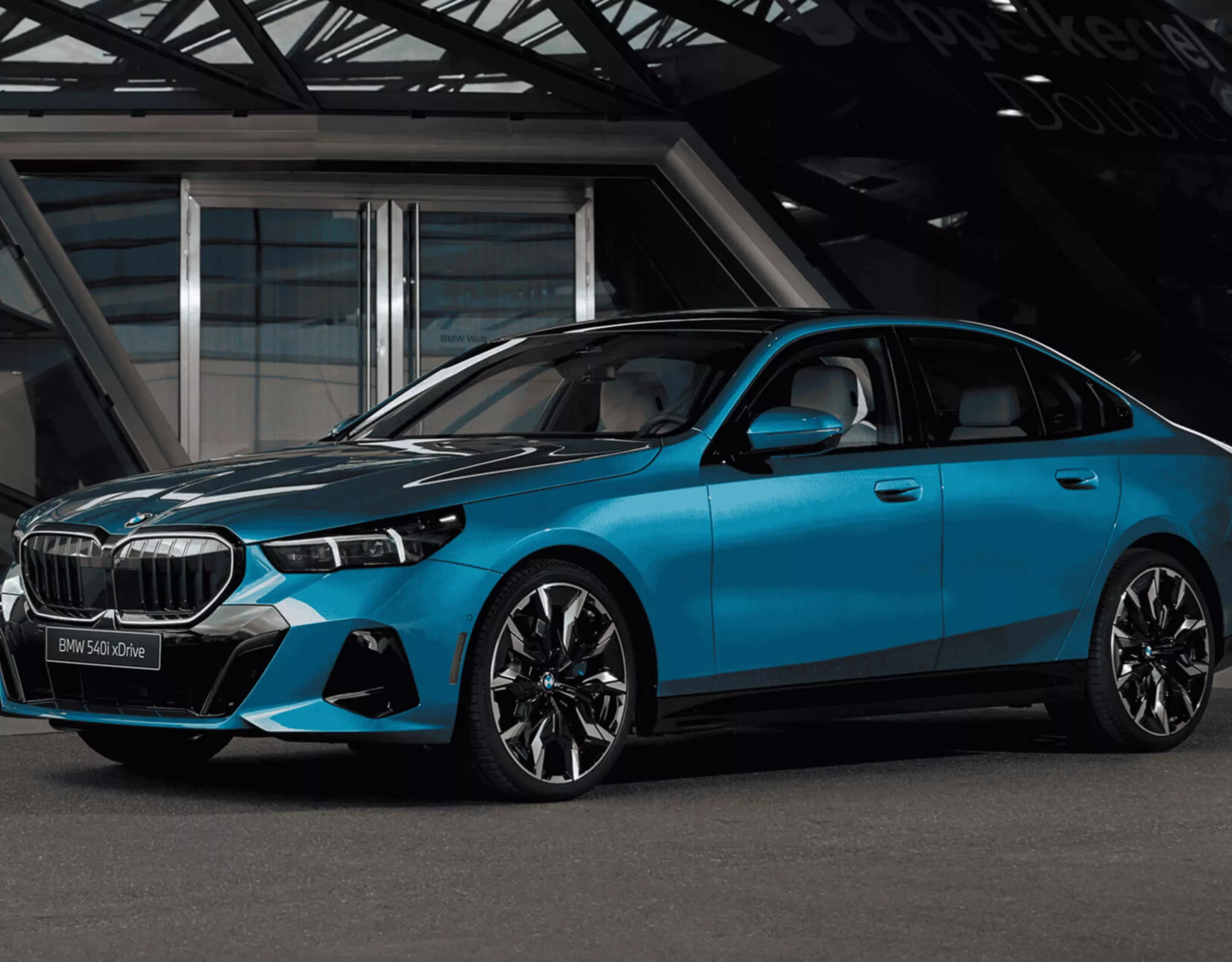 A BMW iX3 is parked in a designated parking zone at the curb, which is lined by plants 