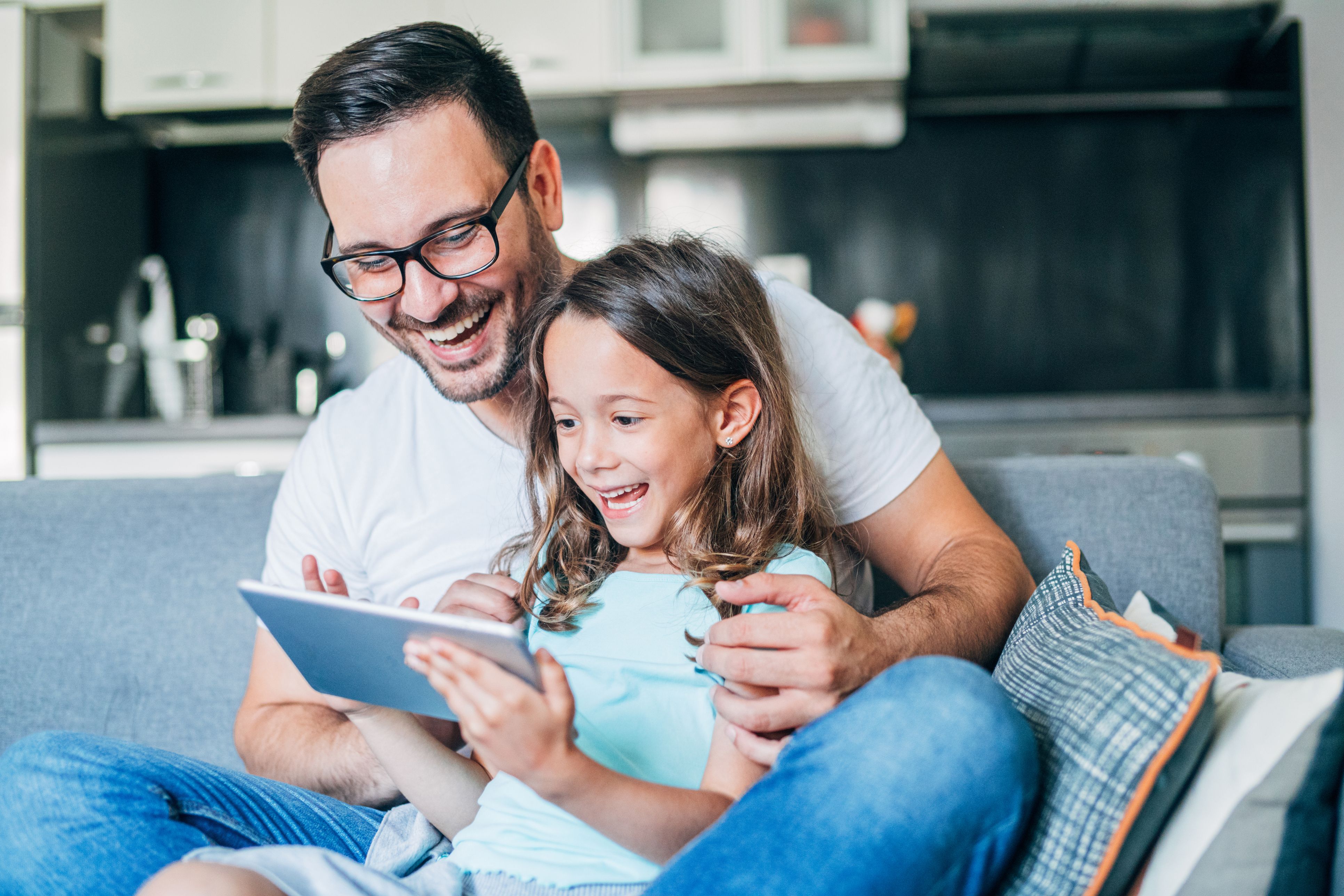 Mann und Kind schauen gemeinsam in Tablet