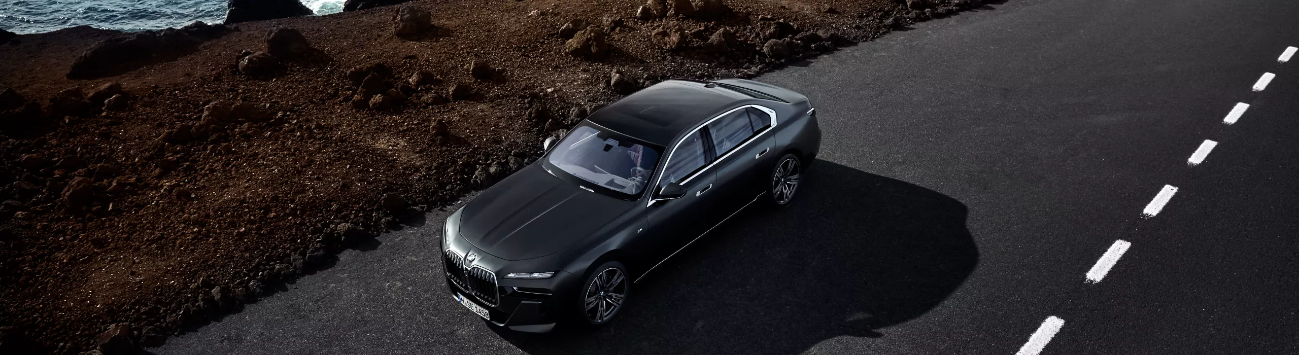 BMW i7 on a gravel road with thunderclouds in the sky