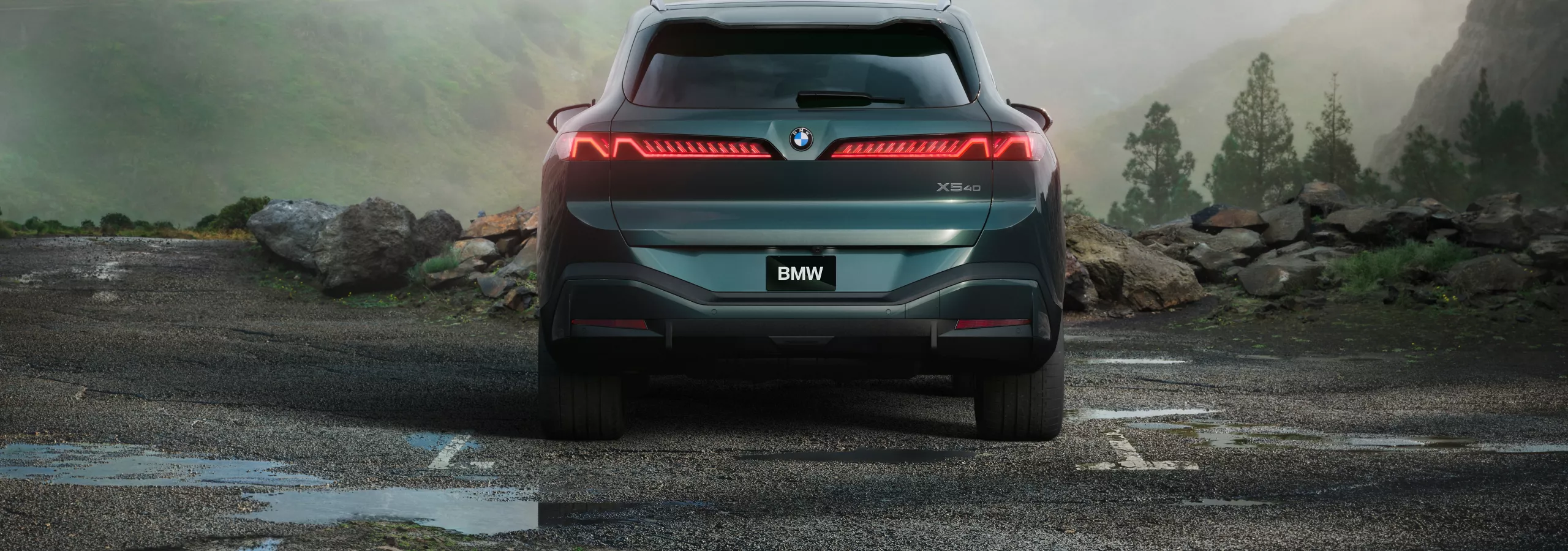 The rear of the BMW X5 parked in front of a mountainous valley