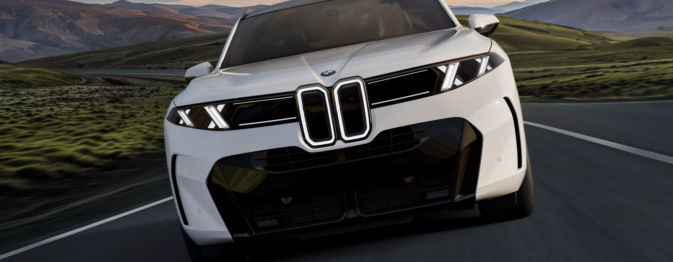 A frontal shot of the BMW X5 50e xDrive as it drives down a highway at dusk.