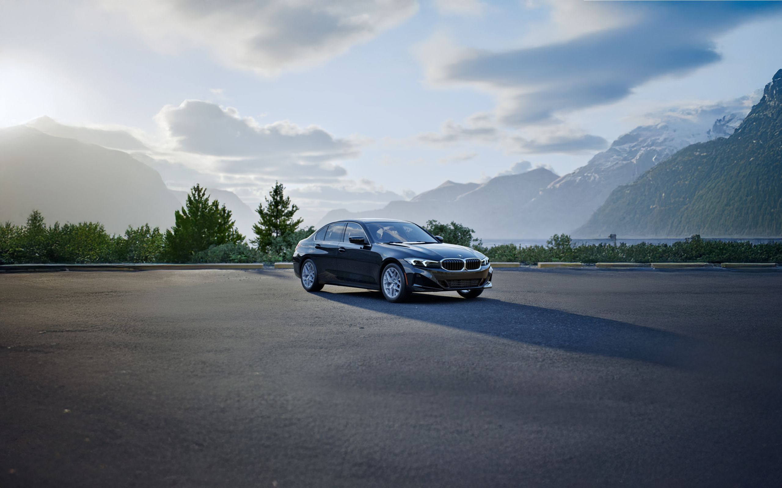 The BMW 330i xDrive parked in front of a mountain landscape with a dramatic shadow underneath the vehicle.