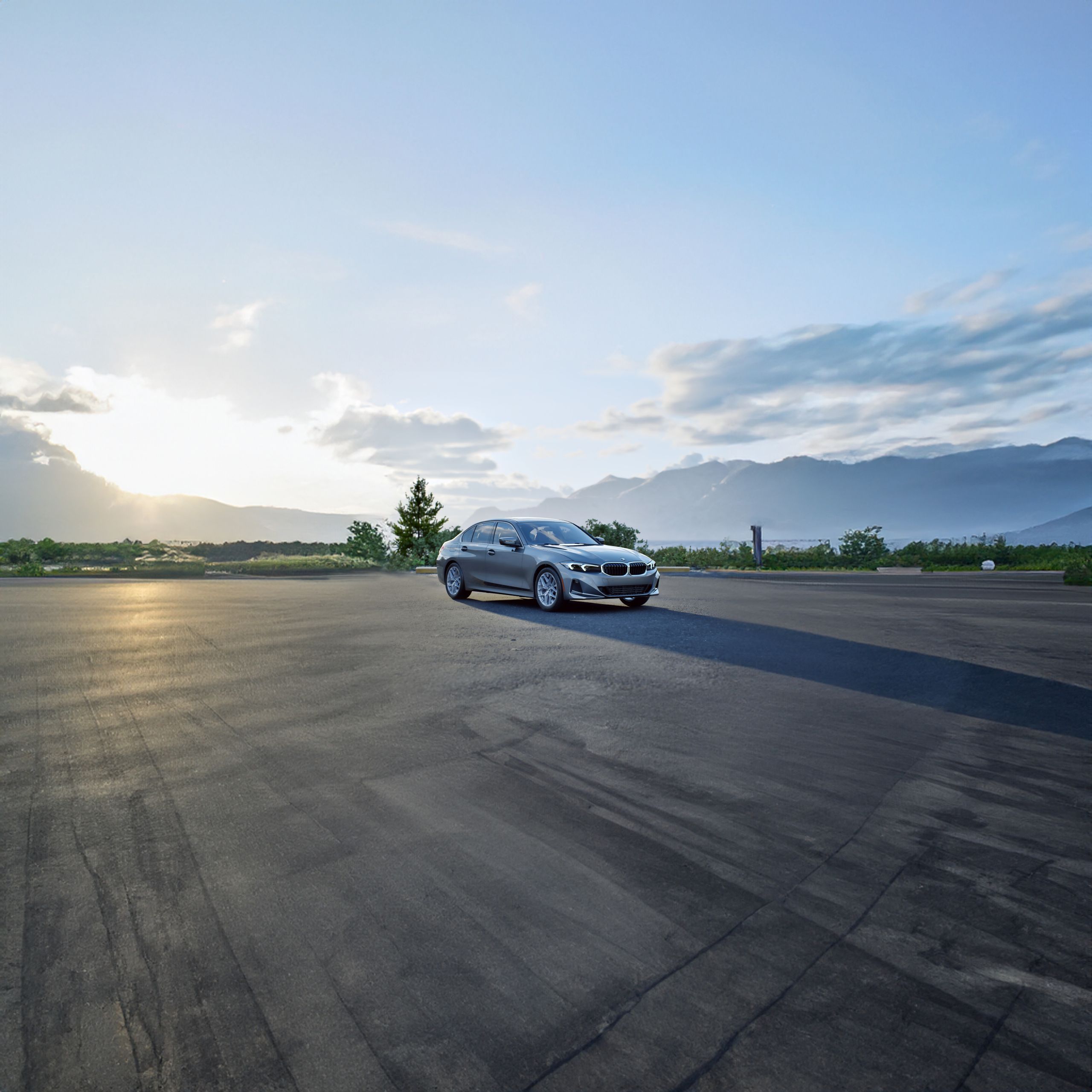 The 330i xDrive parked in front of a forested landscape with mountains in the background.