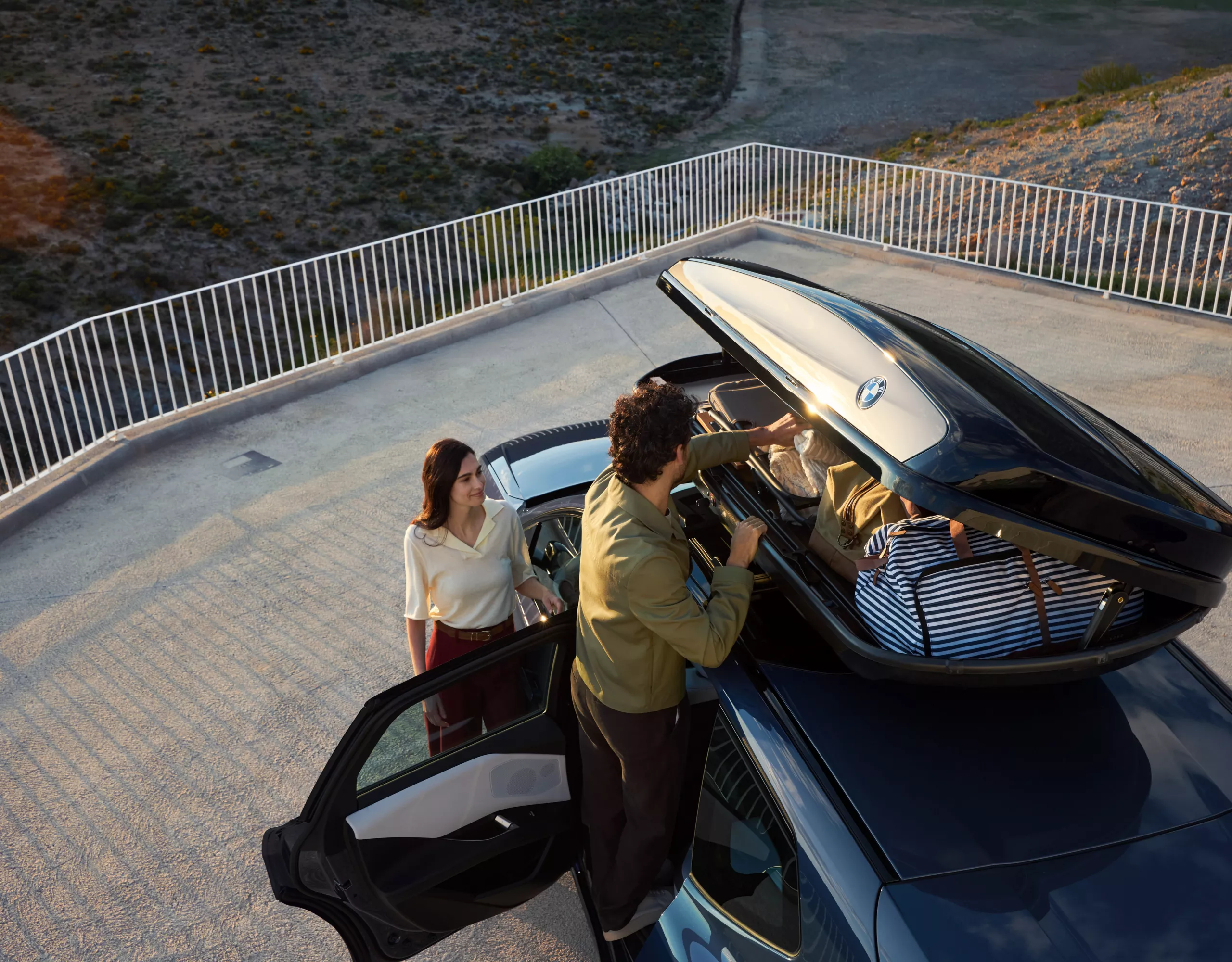 Pärchen lädt Dachbox eines BMW iX3 ein