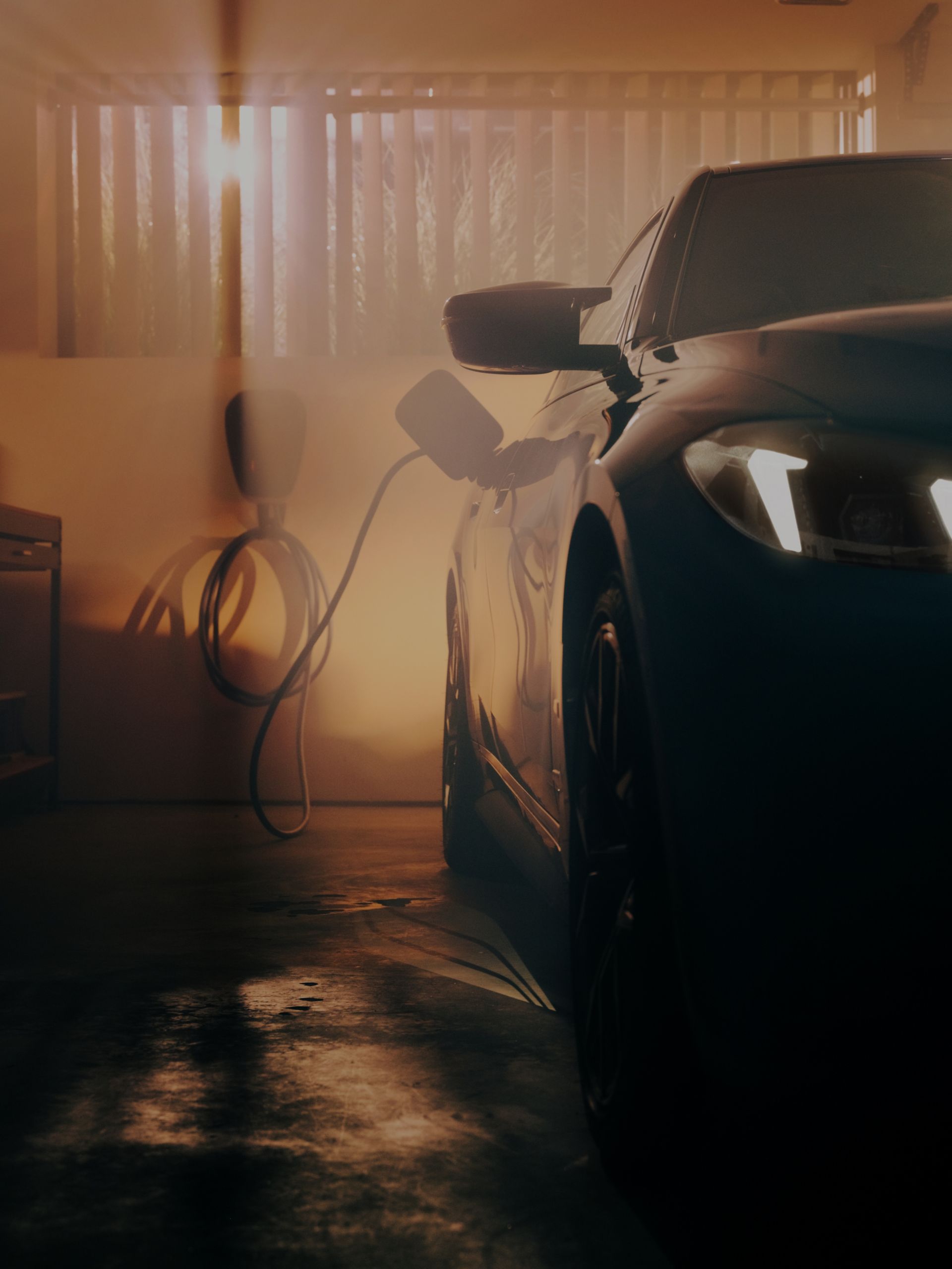 Partial view of an all-electric BMW plugged in, charging in a nighttime setting